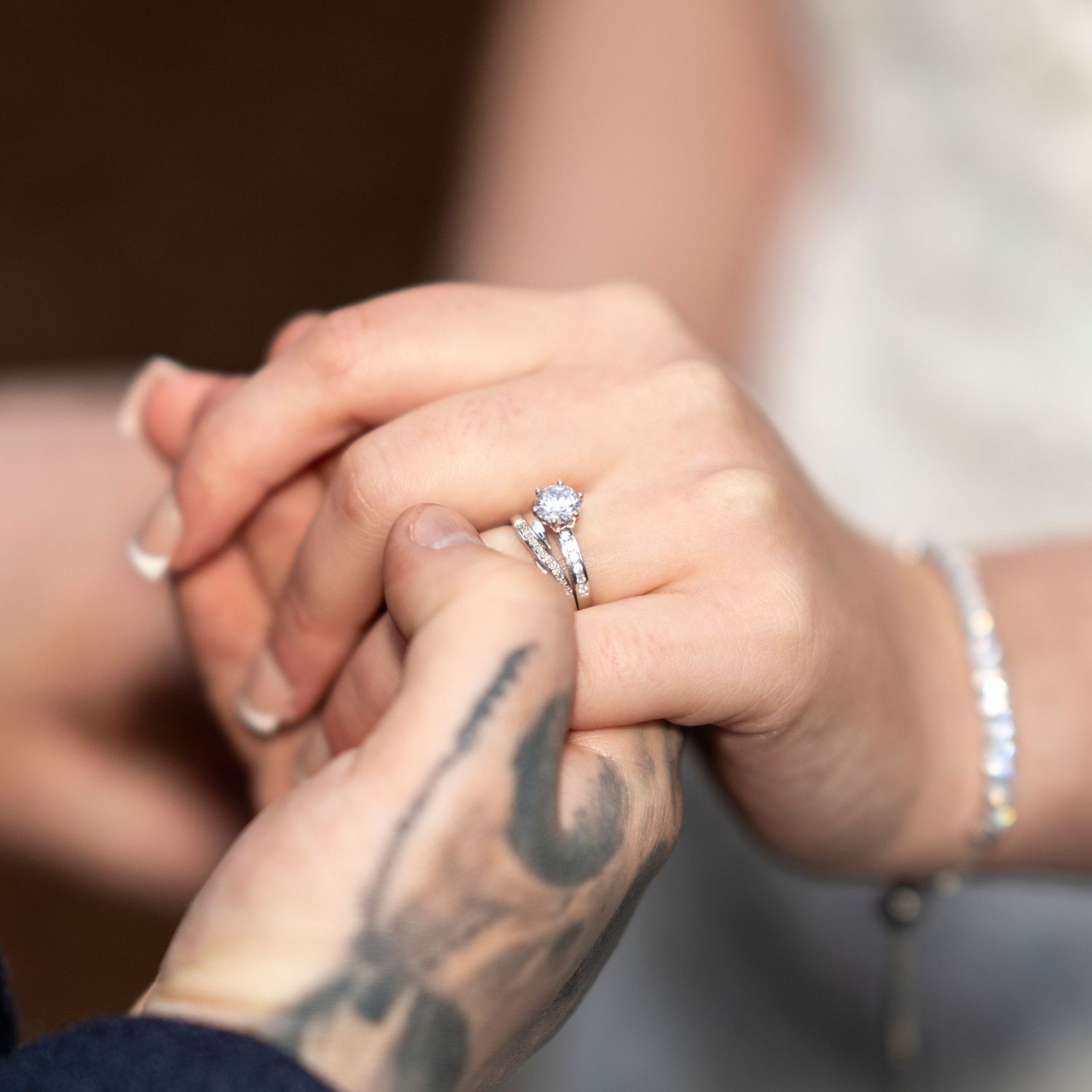 Close-up of bride's diamond engagement ring on hand held by tattooed groom. Dave Martin Photographer Northern Ireland