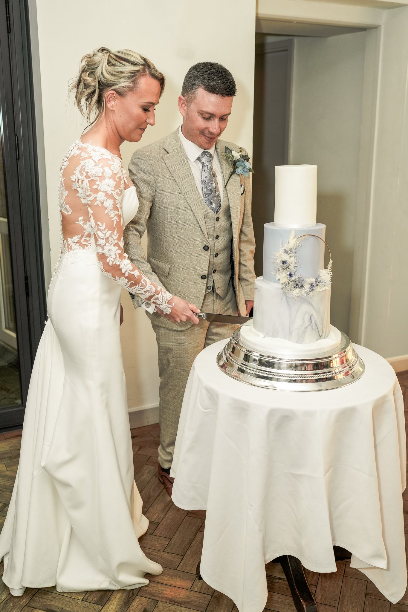Bride and groom cutting their elegant three-tier marble wedding cake at their wedding reception.