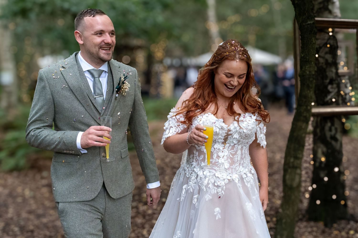 Smiling bride and groom walking through woodland wedding venue. Dave Martin Photographer Northern Ireland