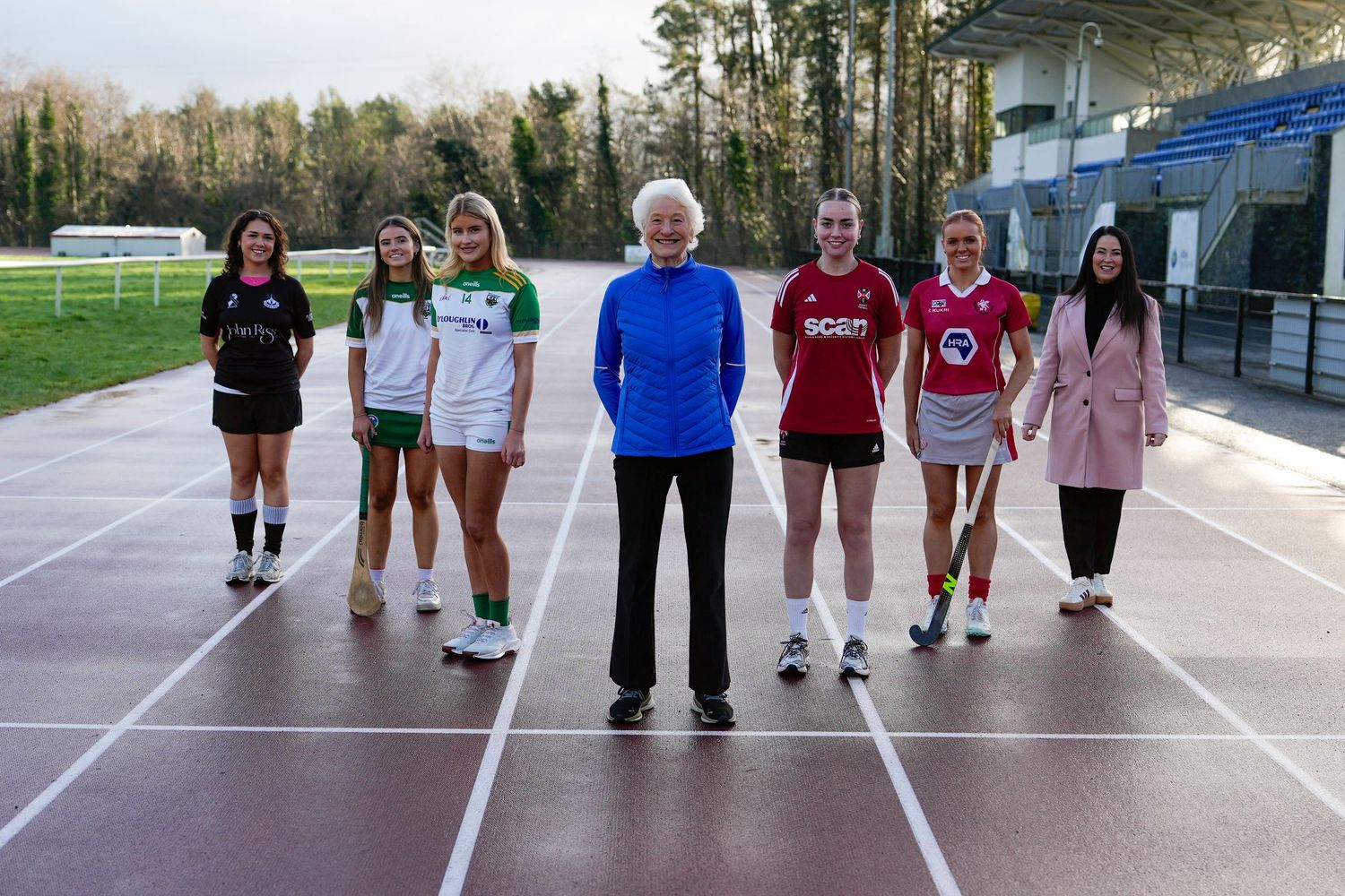 Seven women standing on athletics track in sports jerseys at outdoor stadium. Dave Martin Photography Northern Ireland