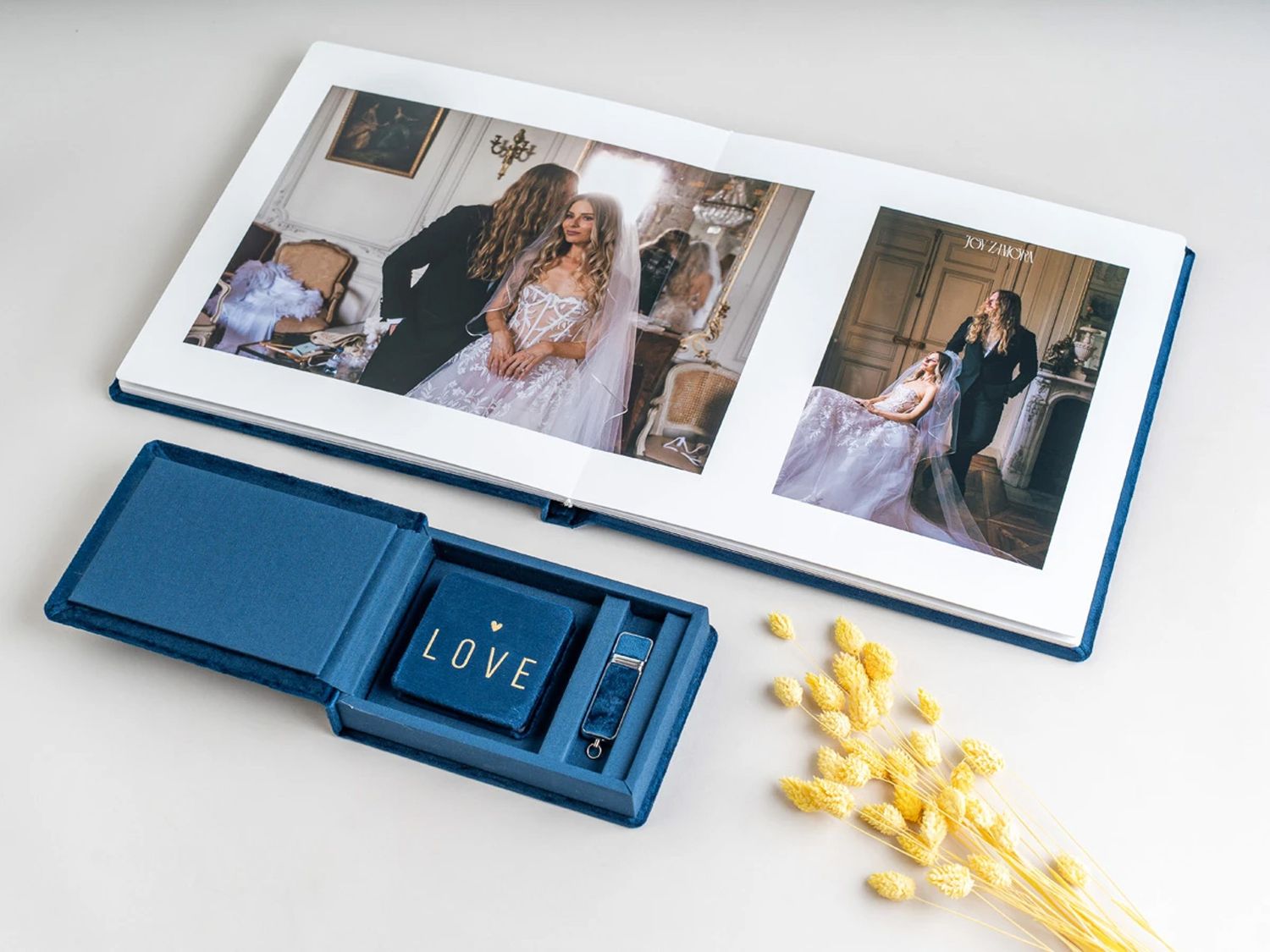 Navy blue wedding photo album with love USB box beside yellow flowers, displaying elegant bride and groom portraits inside. Northern ireland
