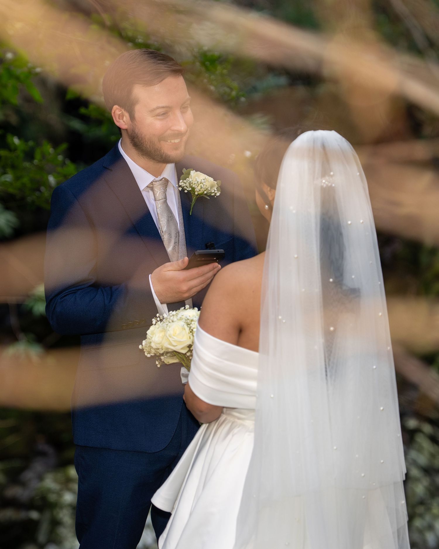 Groom smiling at bride during outdoor wedding ceremony, bride wearing white veil and holding white bouquet. Dave Martin Photography Belfast