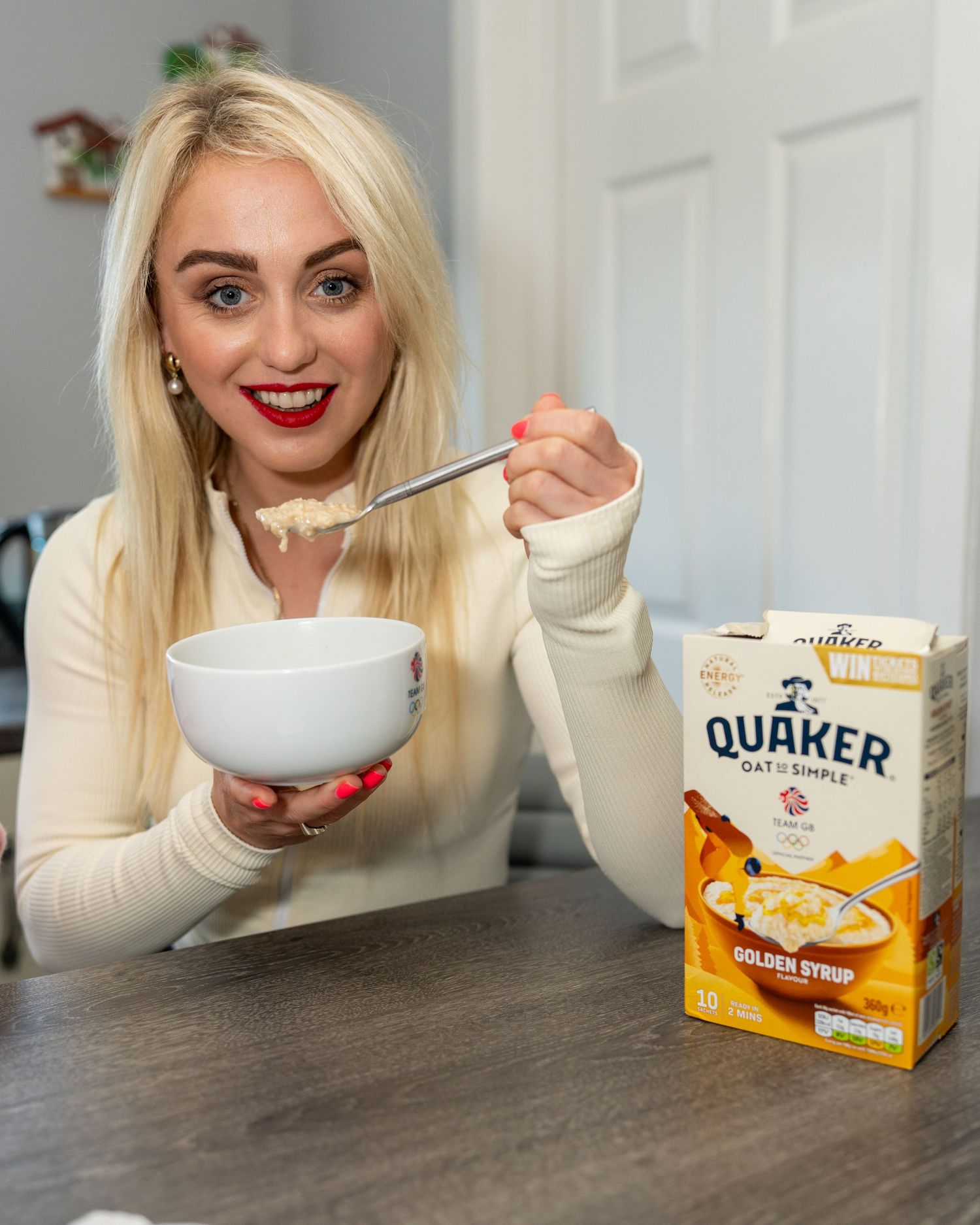 Blonde woman with red lips eating Quaker Golden Syrup oatmeal from a white bowl. Dave Martin celebrity Photography