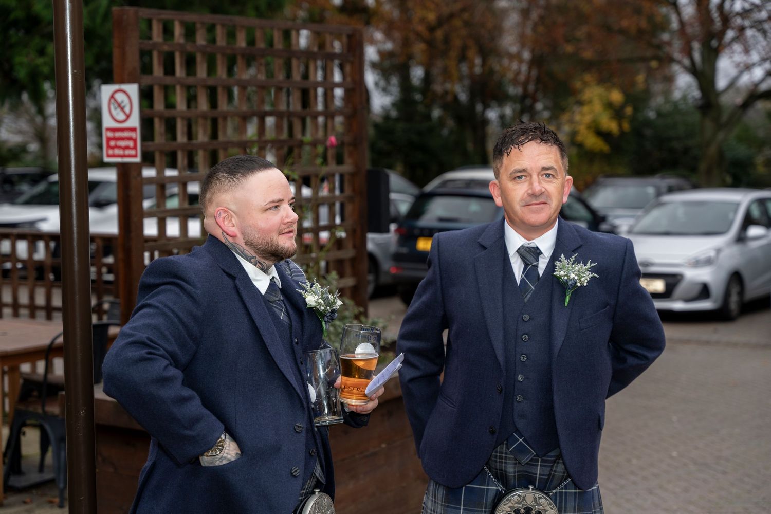 Two men in Scottish kilts and blue jackets standing outside wedding venue. Dave Martin Photographer Northern Ireland