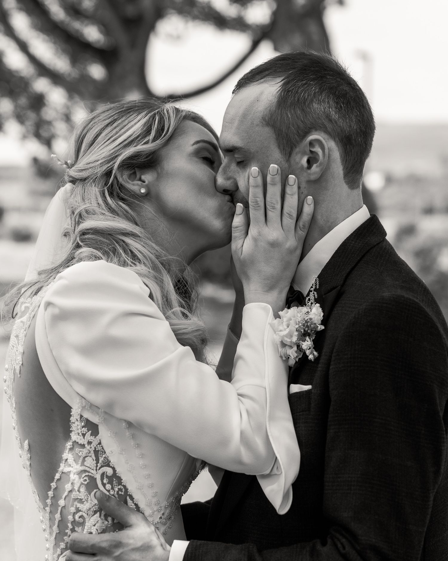Black and white wedding photo of bride and groom sharing a kiss, bride tenderly holding groom's face. Dave Martin photographer Wedding ni