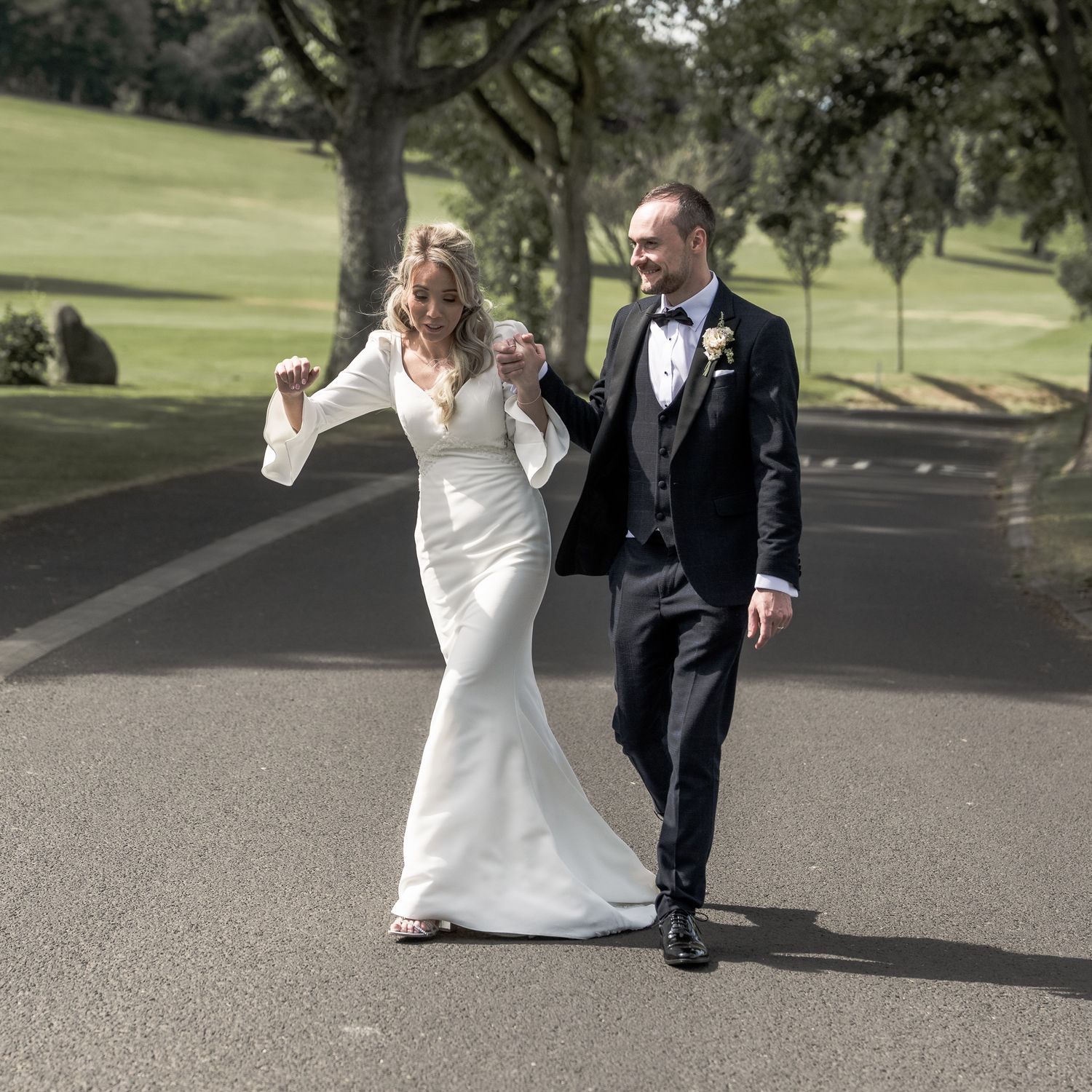 A bride and groom walk hand in hand down a tree-lined path, Northern Ireland Wedding