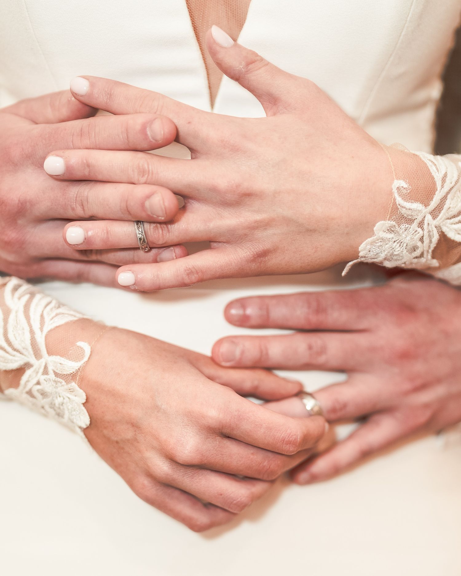 Two couples display wedding rings on lace-sleeved hands, symbolizing marriage and commitment. Dave Martin wedding Photographer NI