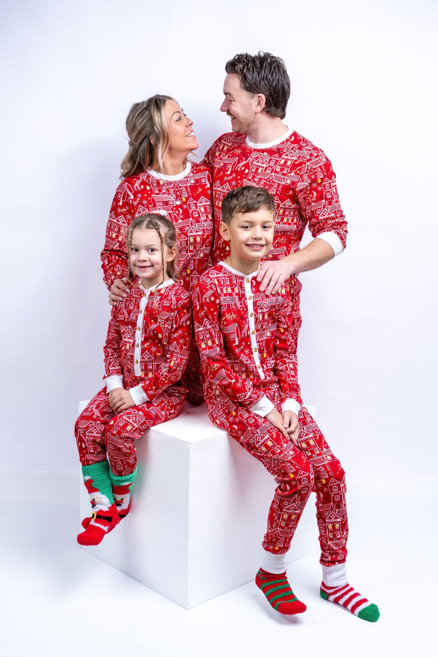 Happy family of four wearing matching red Christmas pajamas posing together. Dave Martin Photography Studio Belfast