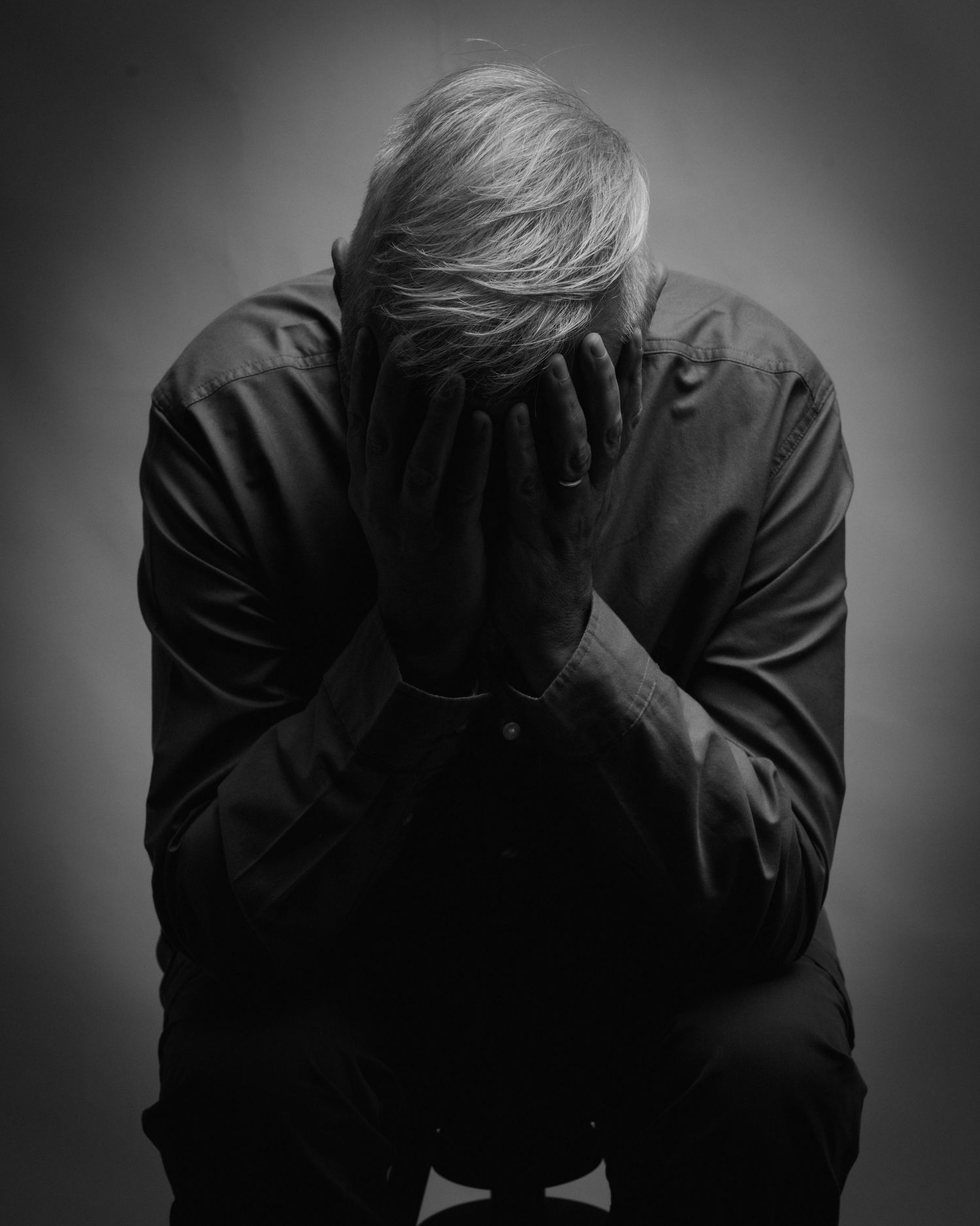 Black and white photo of a distressed elderly man sitting with head in hands. Dave Martin Photography Studio Belfast