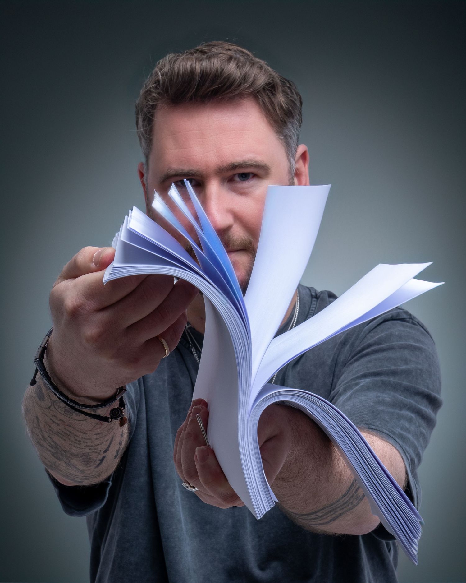 Man holding fanned pages of white paper book toward camera in studio. Dave Martin Photography Studio Belfast