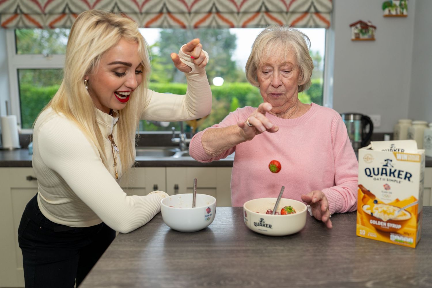 Young blonde woman and elderly lady preparing Quaker Golden Syrup oatmeal in a kitchen. Dave Martin Photography Studio Belfast