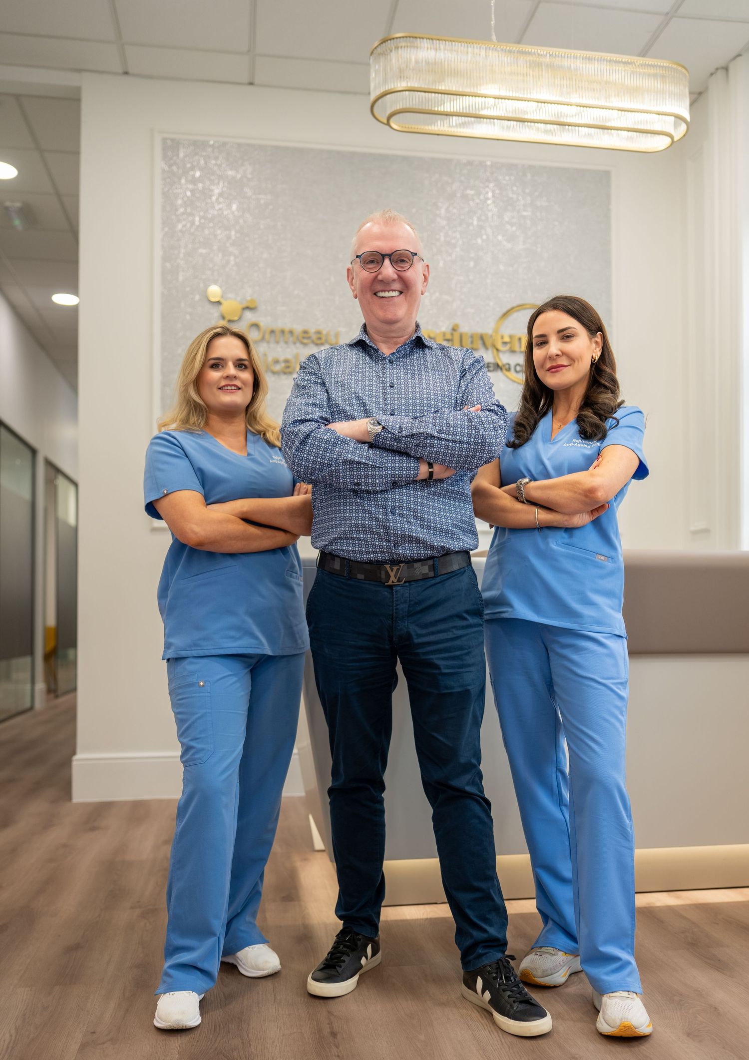 Two women in blue scrubs flanking a man in blue shirt in modern dental clinic. Dave Martin Photography Northern Ireland
