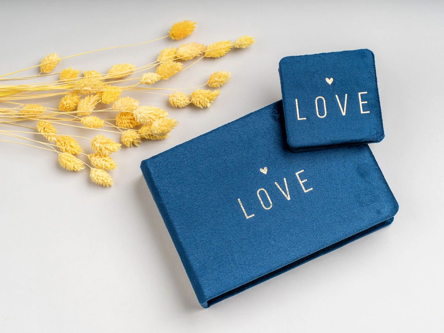 Blue velvet LOVE gift boxes with gold text, styled with yellow dried flowers on a white background. Northern ireland weddings