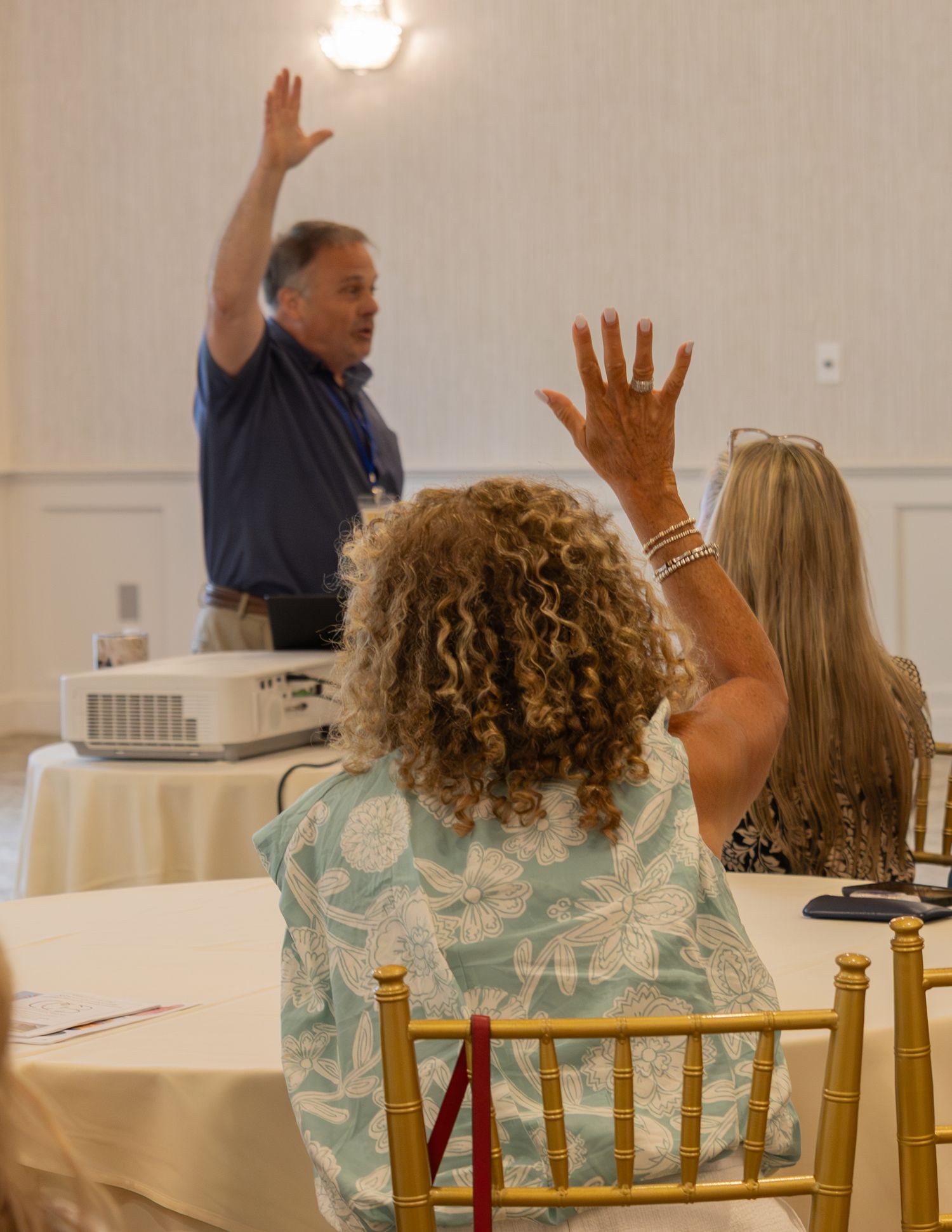 Conference attendee raising hand to ask question during interactive workshop presentation session.