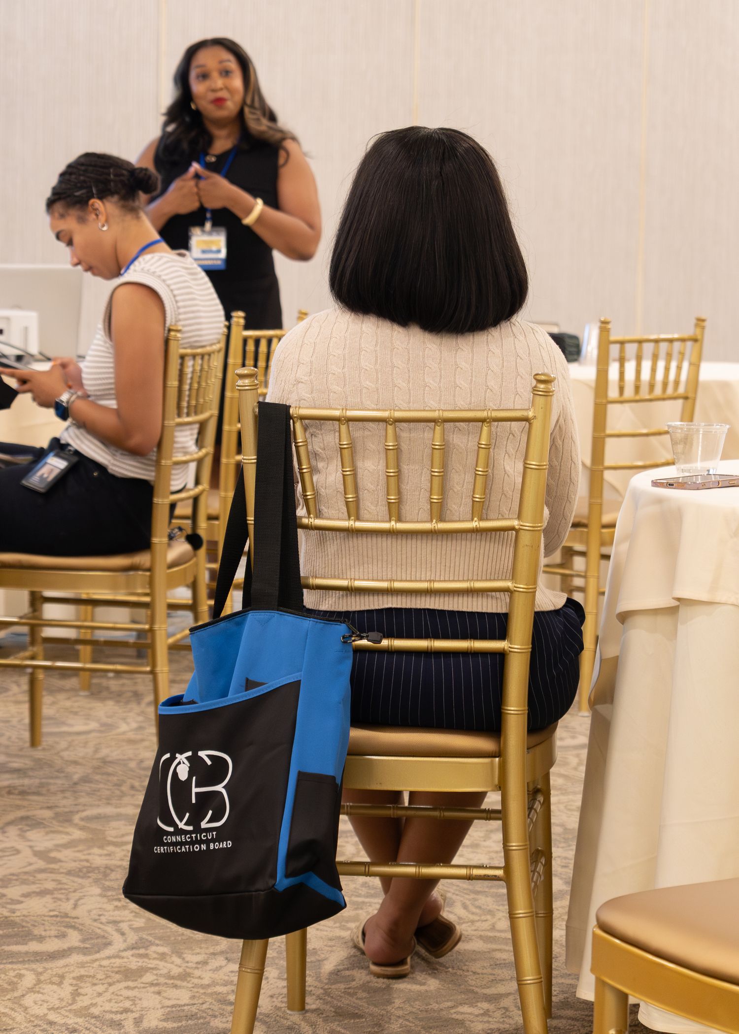 Conference attendee sits in gold chiavari chair with Connecticut Childrens tote bag at seminar.