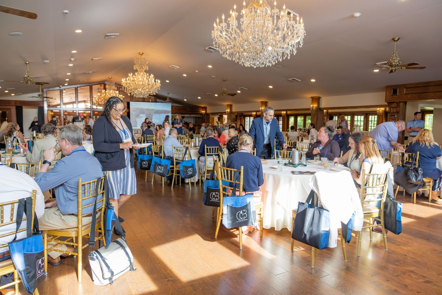 Elegant banquet hall with crystal chandeliers hosting a formal seated corporate luncheon event.
