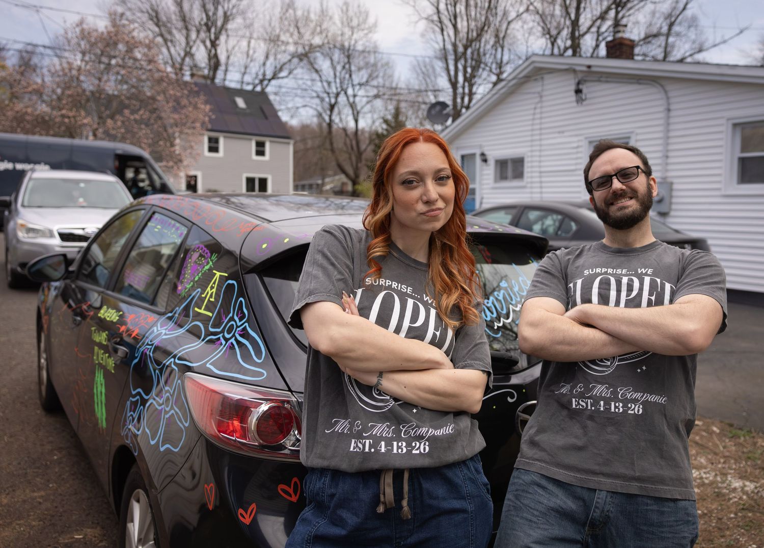 Newlywed couple standing proudly in front of their decorated wedding car with Lopez Est. signage.