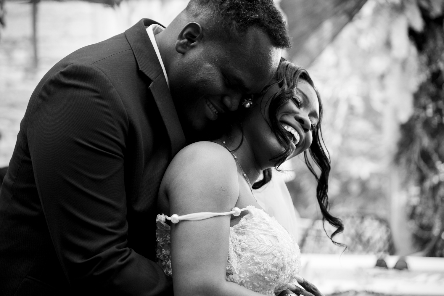 Black and white wedding photo of a joyful couple sharing an intimate moment, bride and groom laughing together.