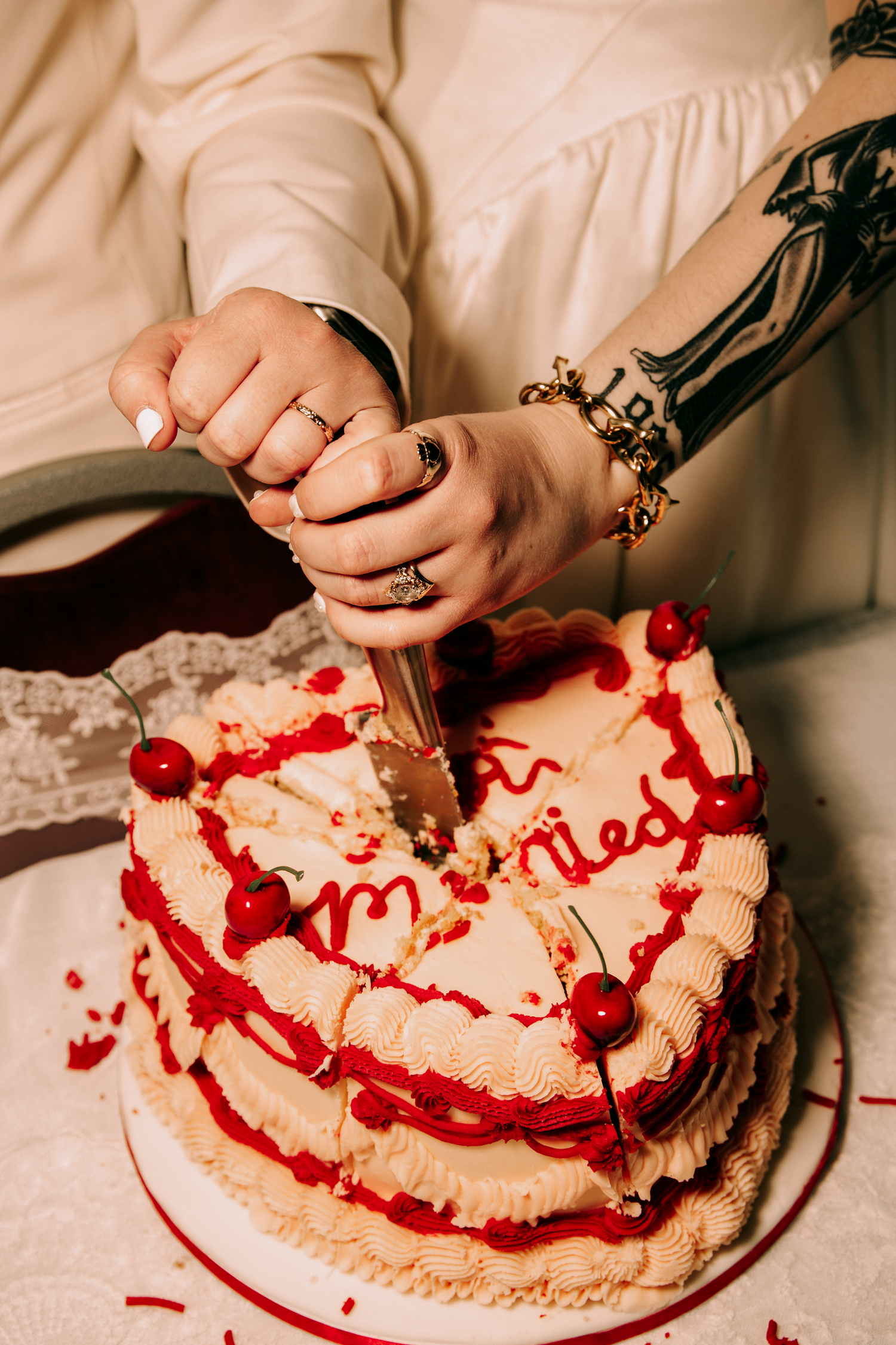Bride and groom cutting a heart-shaped wedding cake decorated with red cherries and cherry sauce piping.