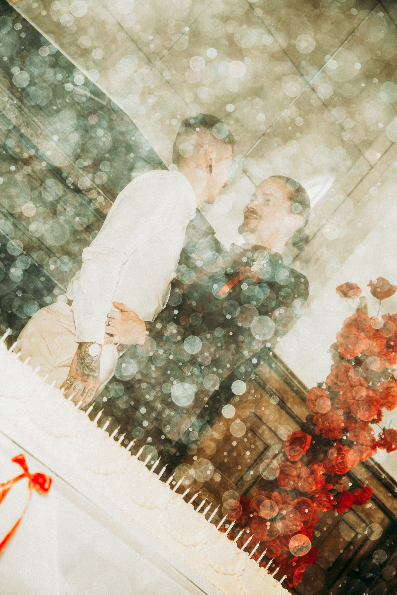 A dreamy double exposure photo of two grooms sharing a romantic kiss on their wedding day.