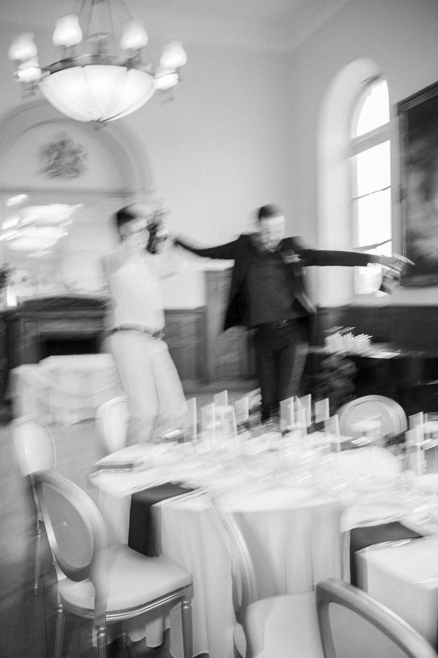 Black and white blurred motion photo of two grooms dancing at elegant wedding reception.