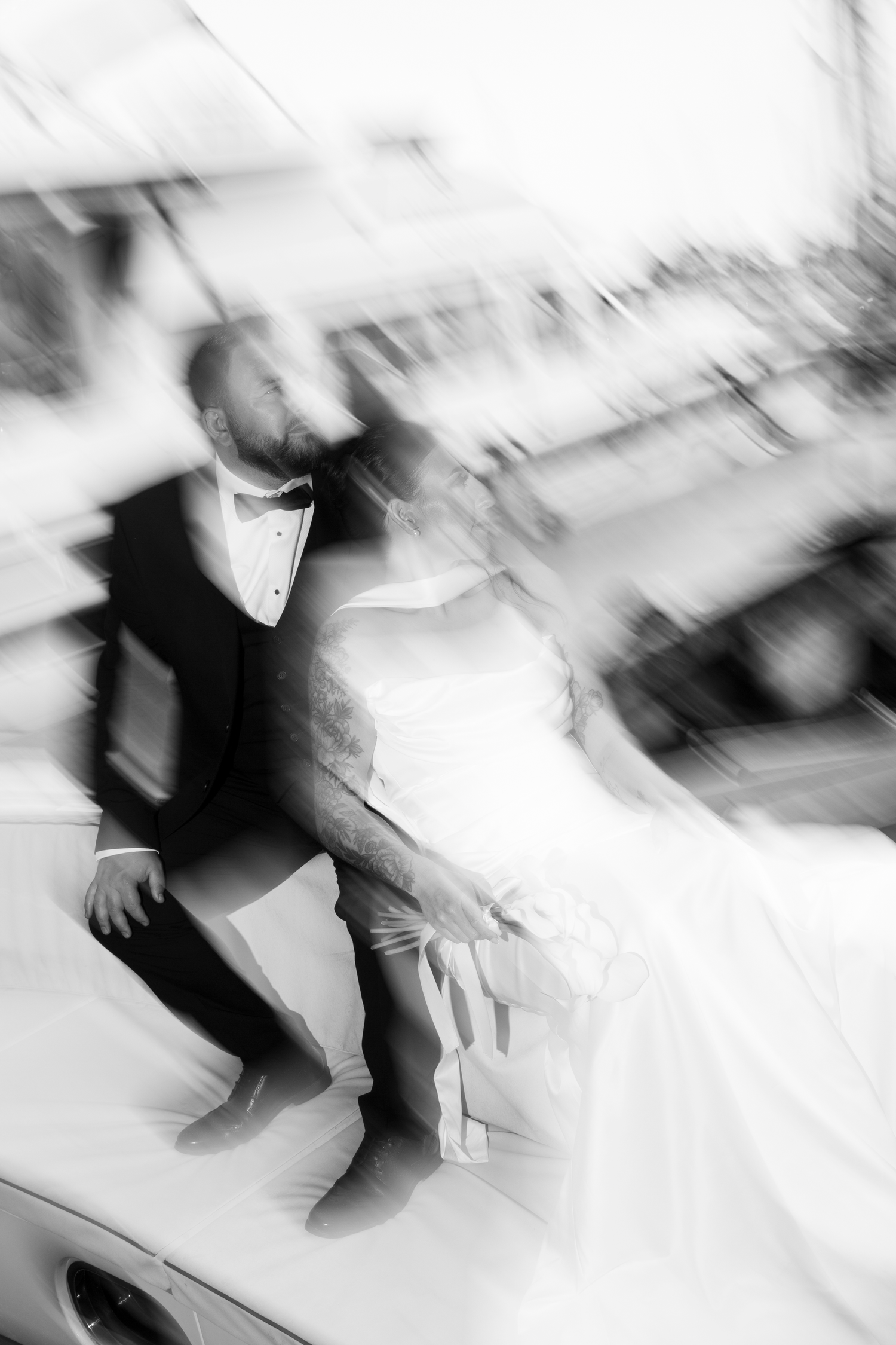 Artistic blurred black and white photo of bride and groom posing on a boat at marina.