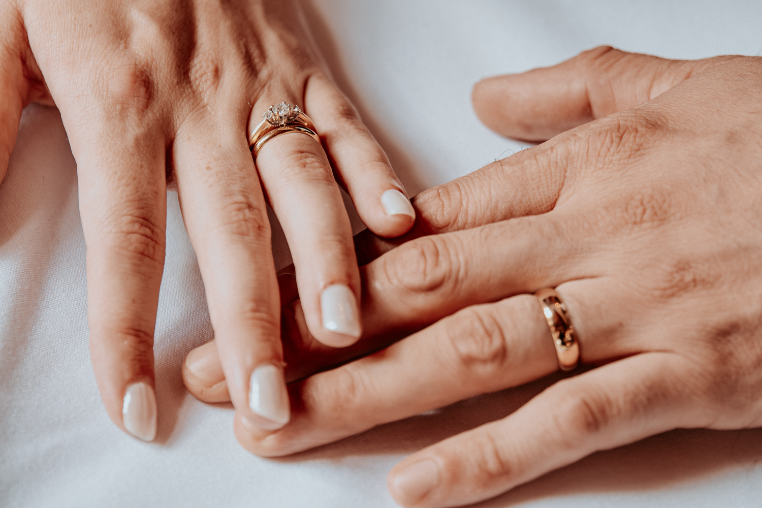 Two hands with wedding rings resting together, symbolizing marriage and commitment.