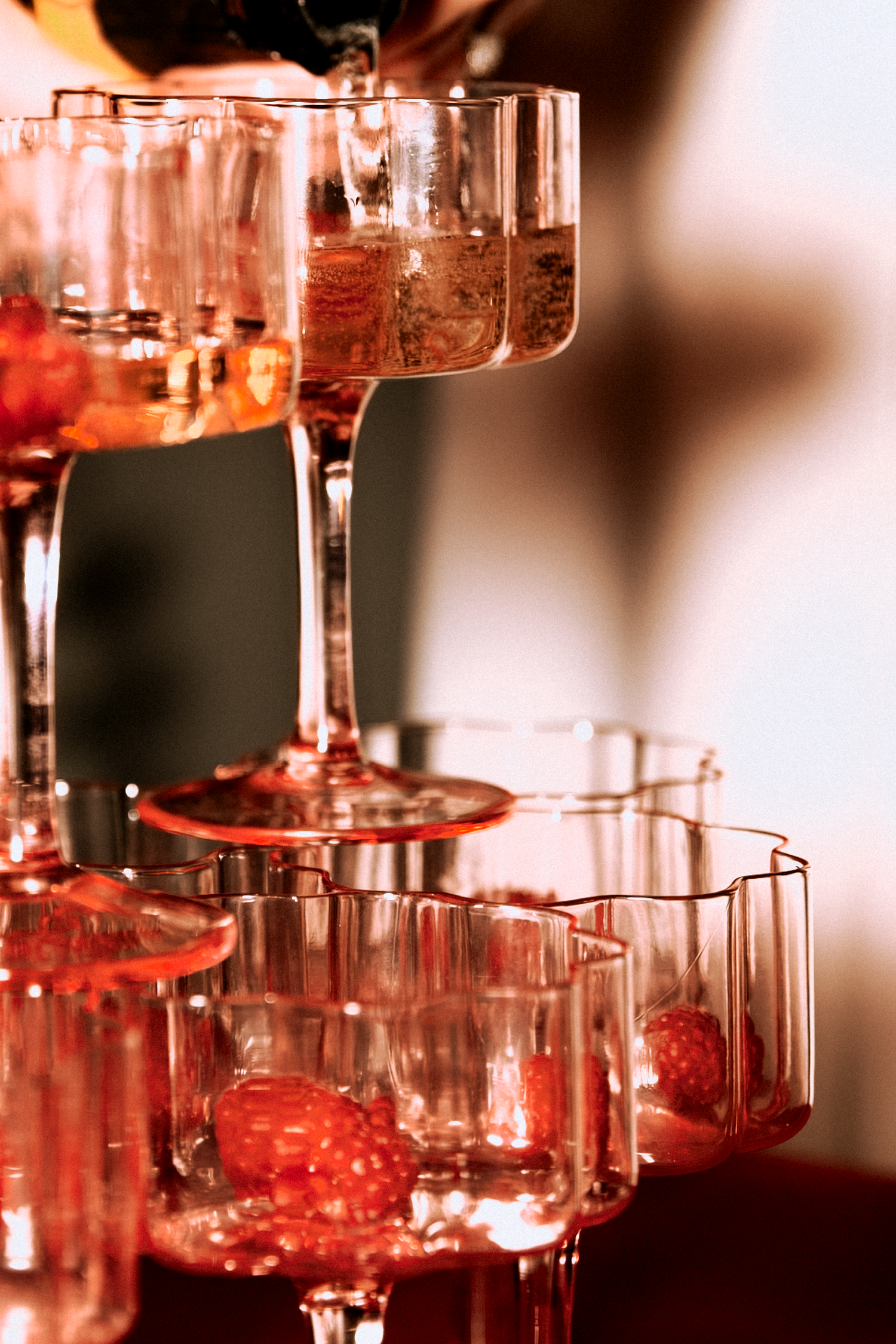 Champagne tower with strawberries being poured at a wedding celebration.