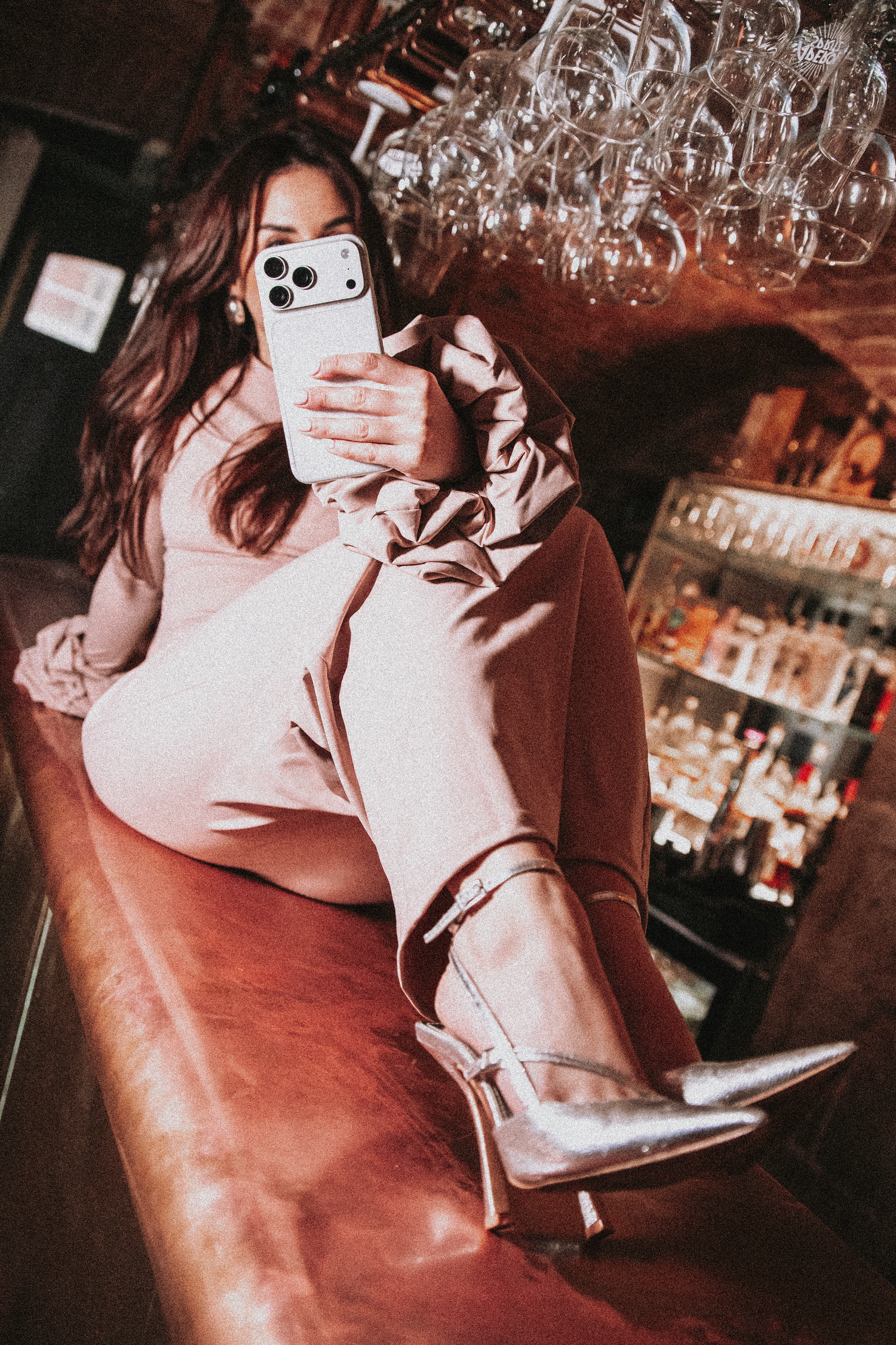 Young woman in pink outfit taking a selfie while relaxing at a bar counter. Content Creator Branding Shoot.