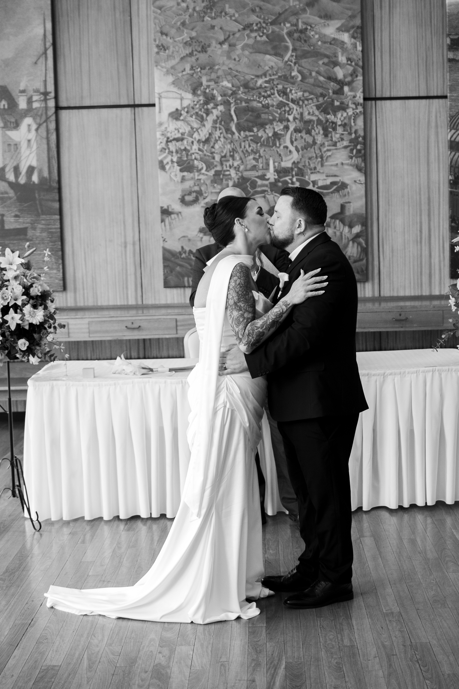Bride and groom share their first kiss at the altar in a classic black and white wedding photo.