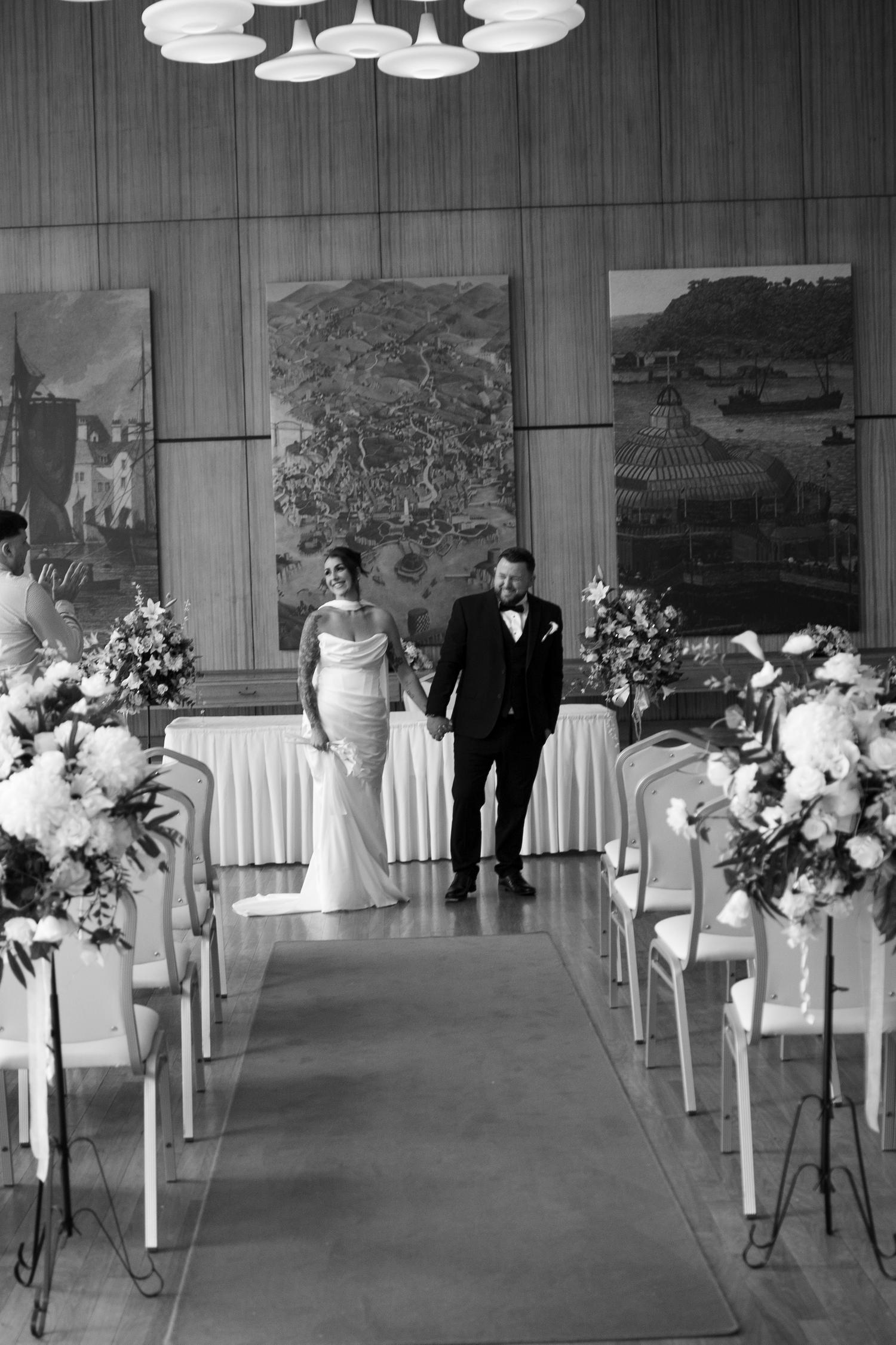 Bride and groom walk down the aisle together after their wedding ceremony in an elegant decorated hall.