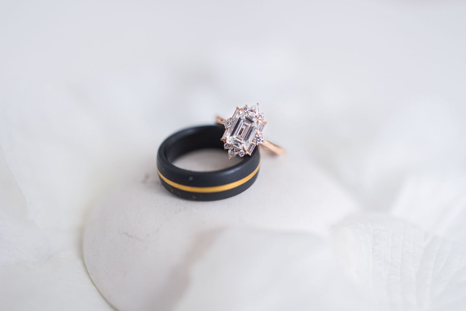 Black and rose gold wedding rings on white fabric.
