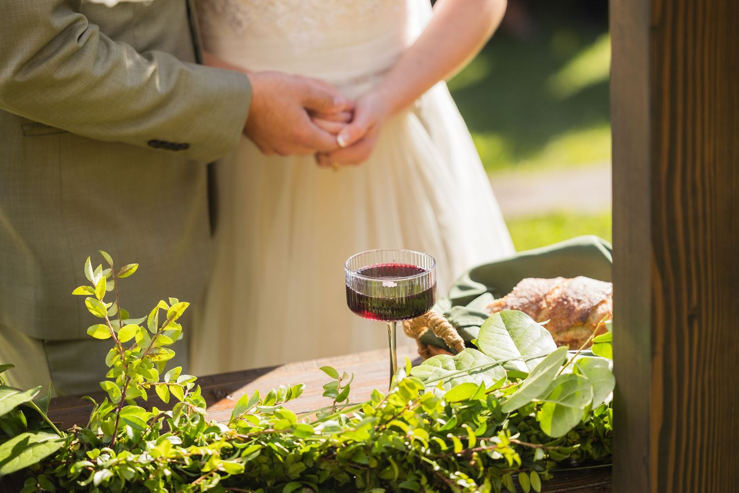 Red wine glass on table with greenery at wedding.