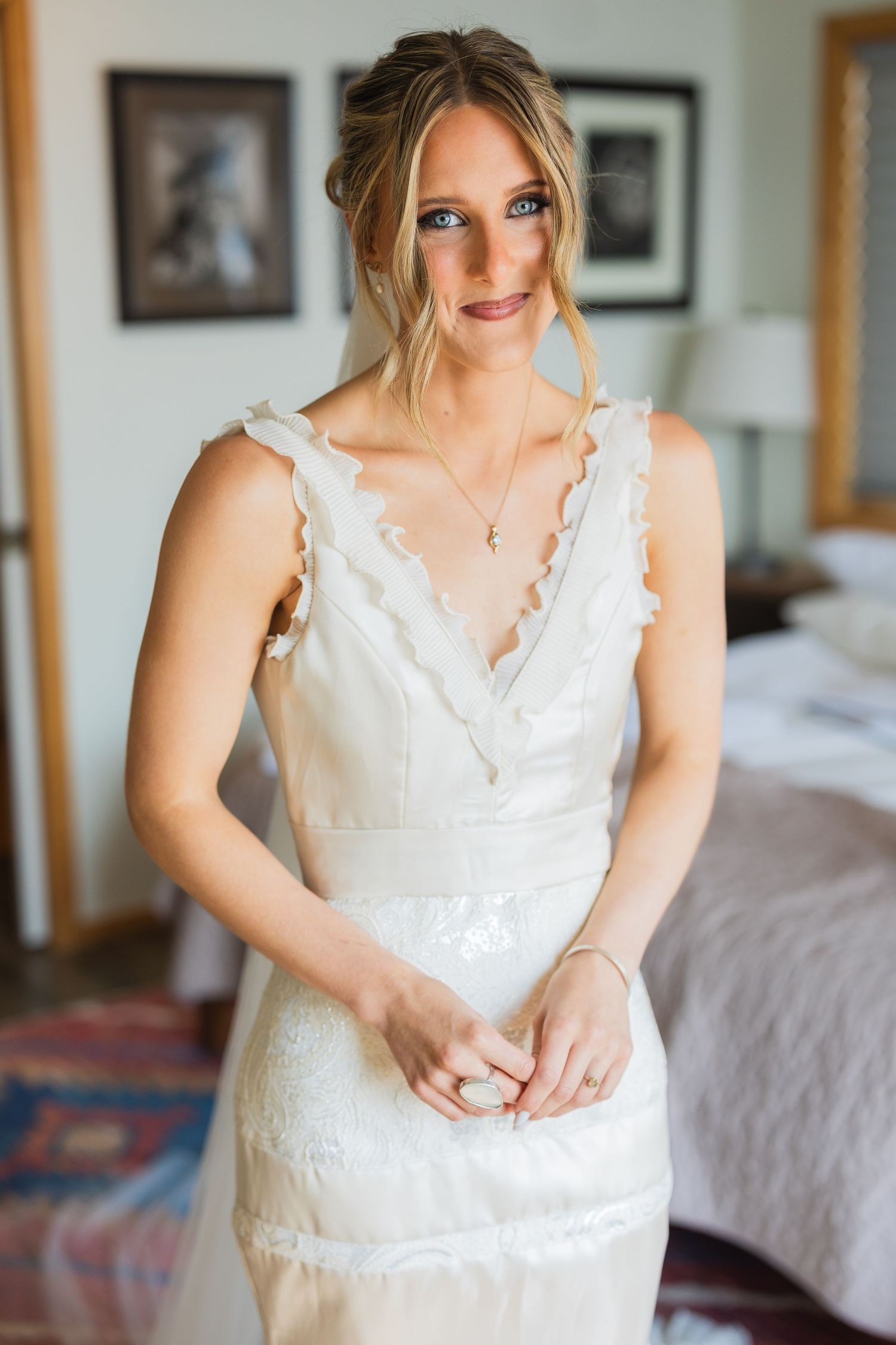 Beautiful bride in a sleeveless lace V-neck wedding gown posing indoors on her wedding day.