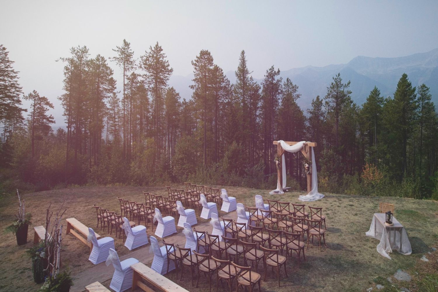 Overhead shot of the wedding ceremony setup with chairs, the aisle, and the altar, with trees and mountains in the background.