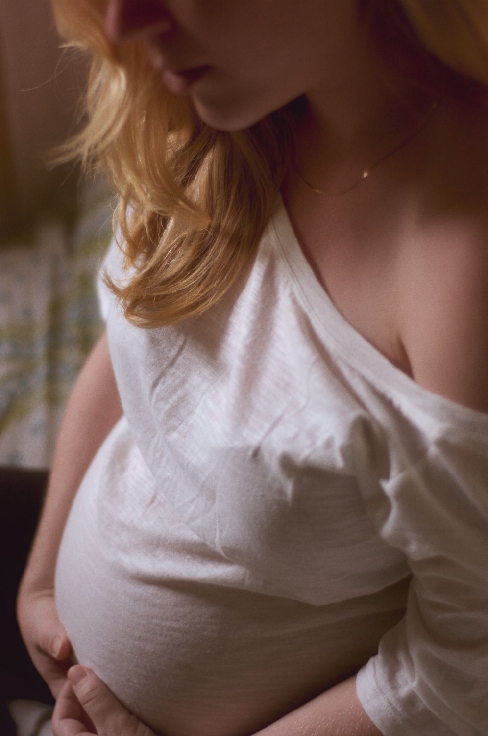 Overhead shot of a blonde pregnant woman sitting up, showing her hair, shoulder, and belly.