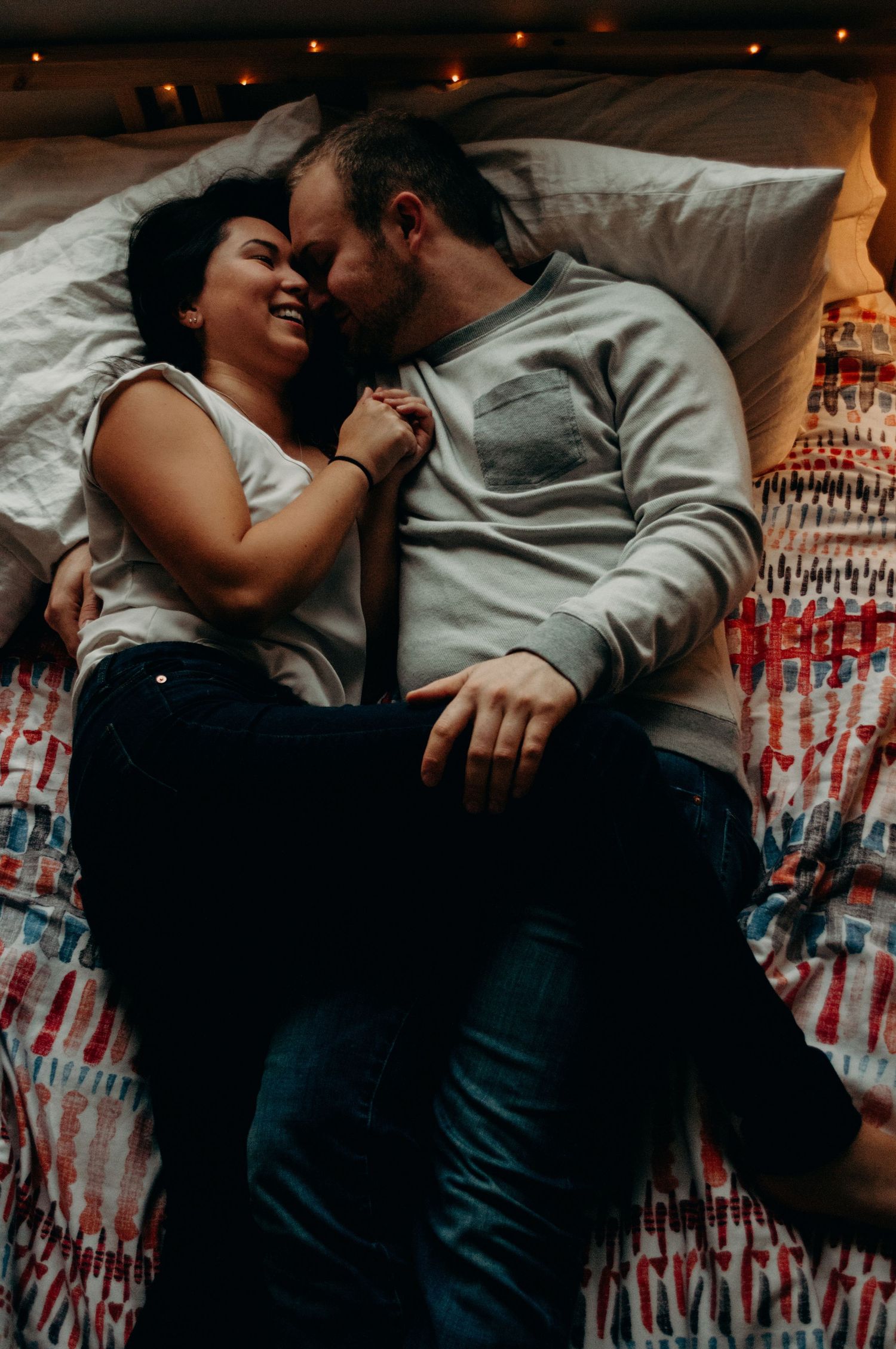 Couple smiling and snuggling in their bed.