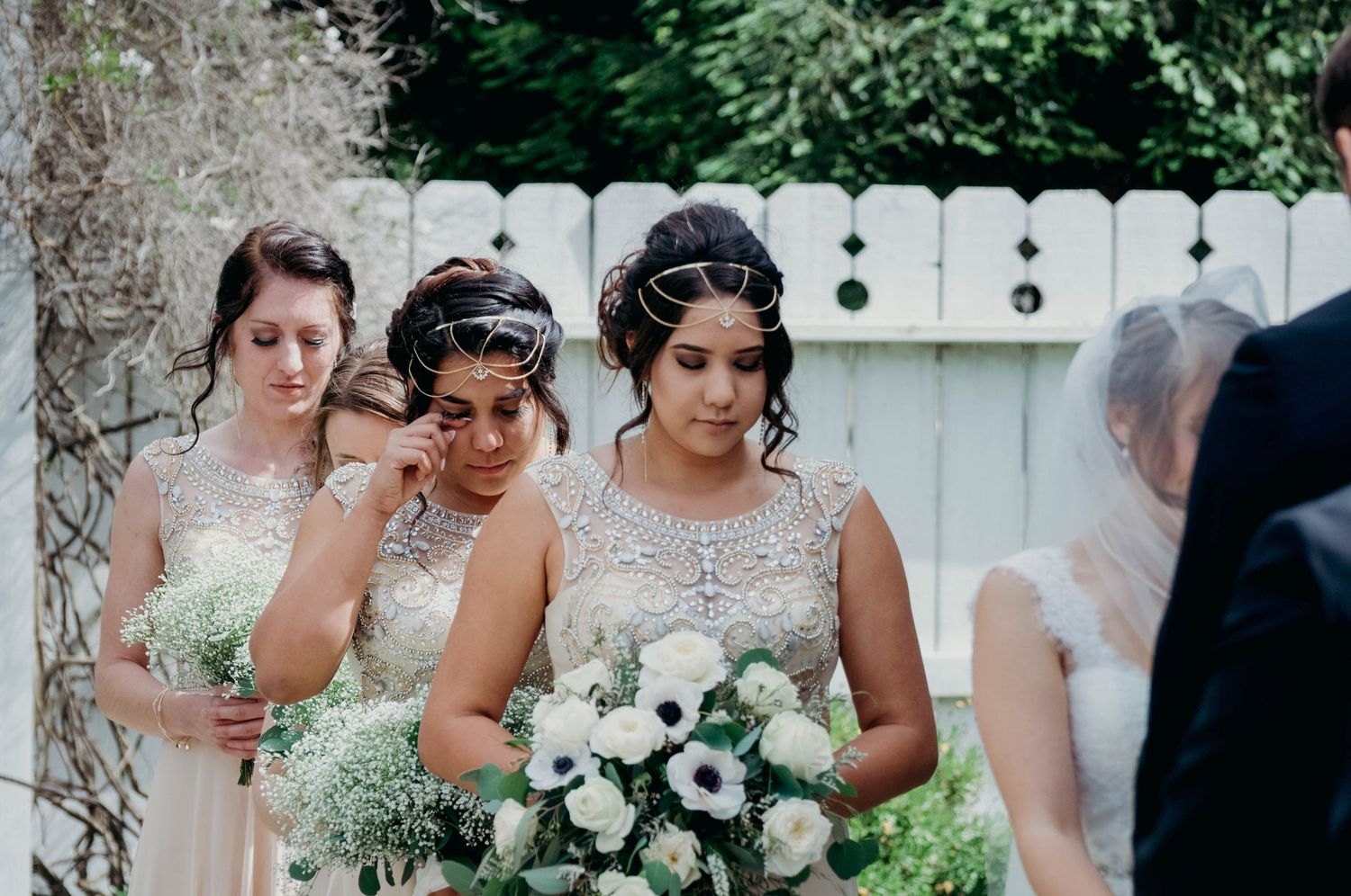Bridesmaids tearing up standing behind the bride during the ceremony.