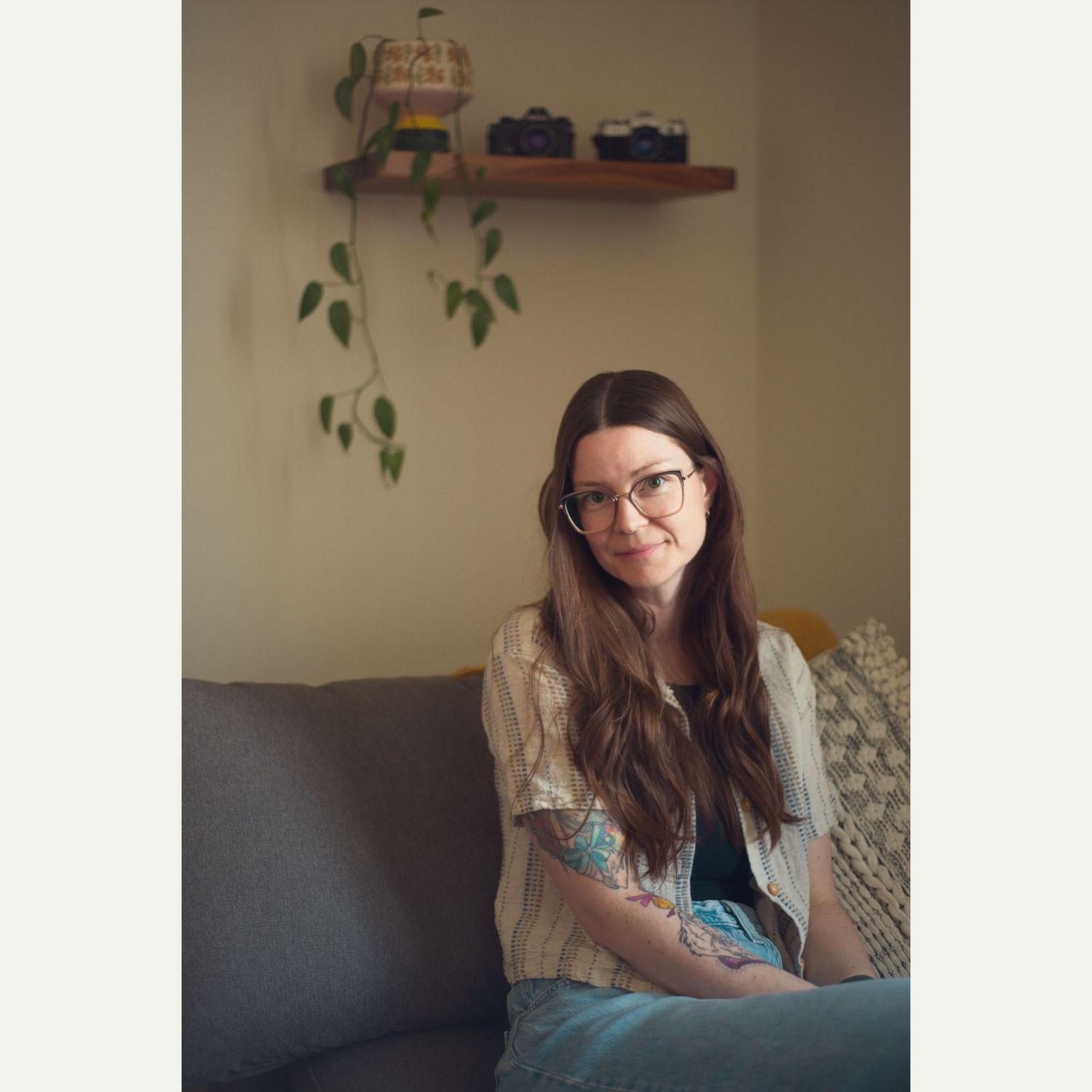 Photographer sits on a couch and looks calmly at the camera.