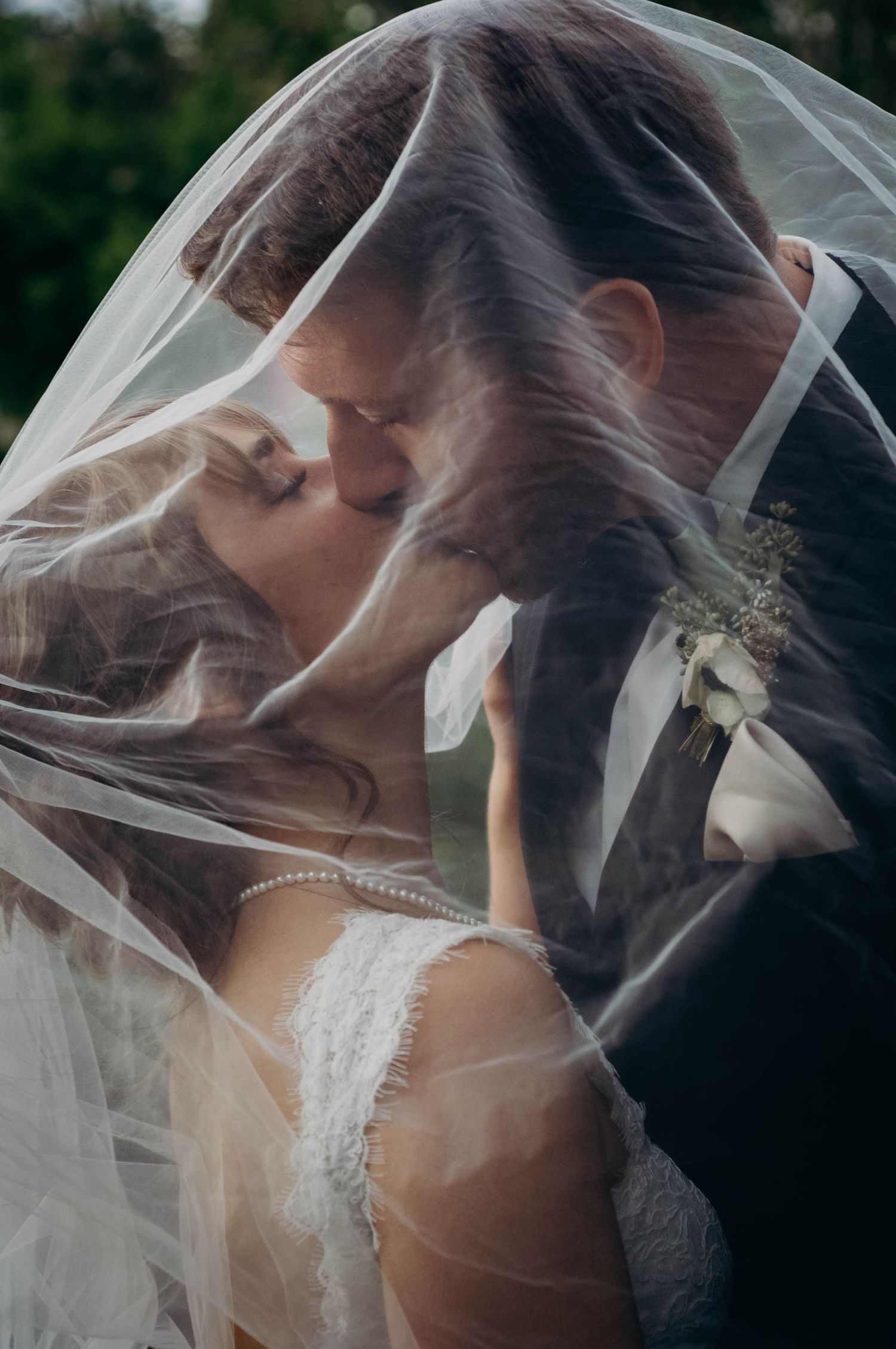 Bride and groom share a kiss under the bride's veil after getting married.