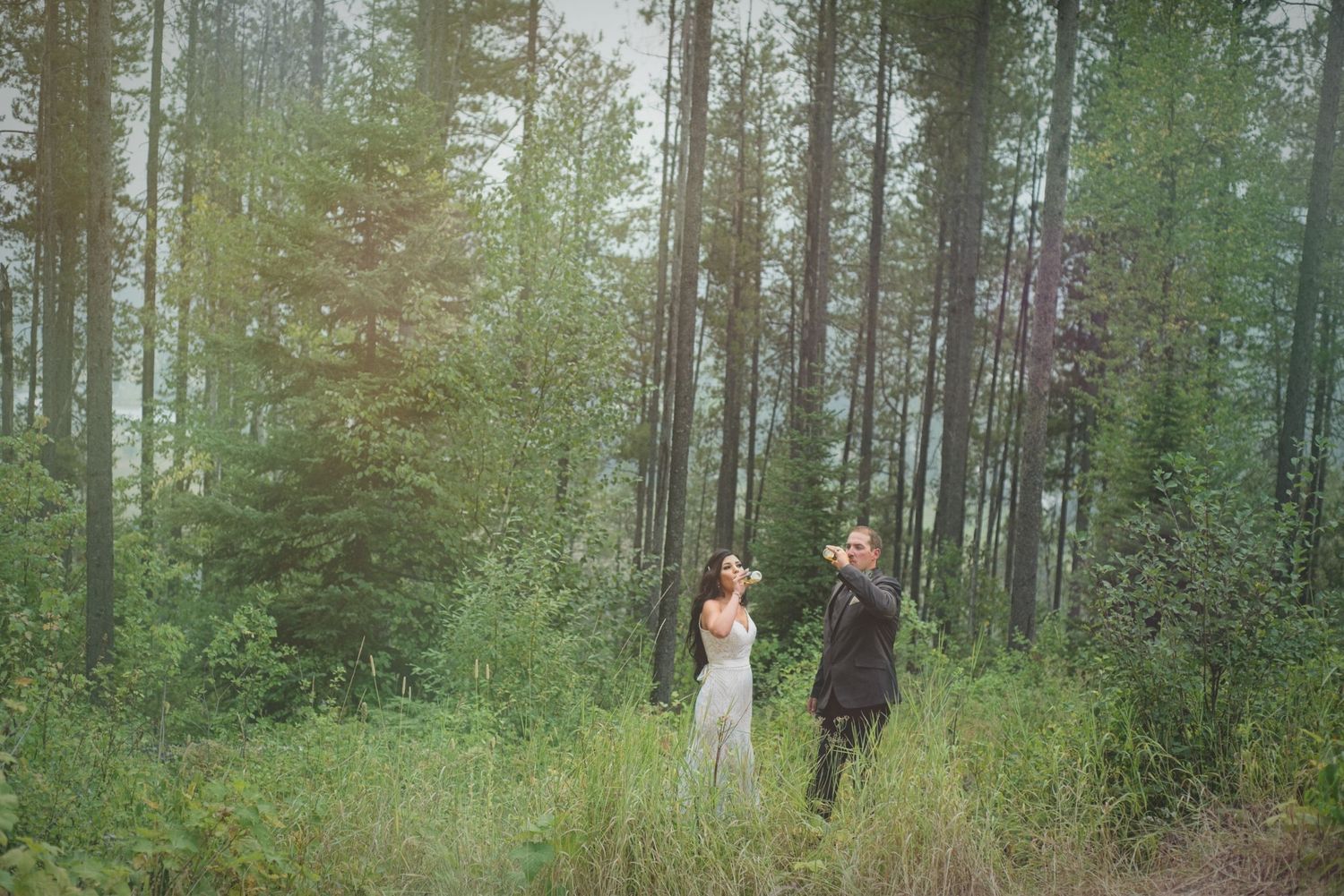 Bride and groom share a beer in the forest following their wedding ceremony.