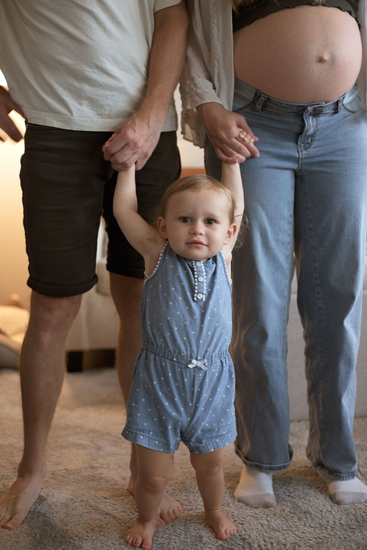 Mom and dad hold the hands of their toddler.