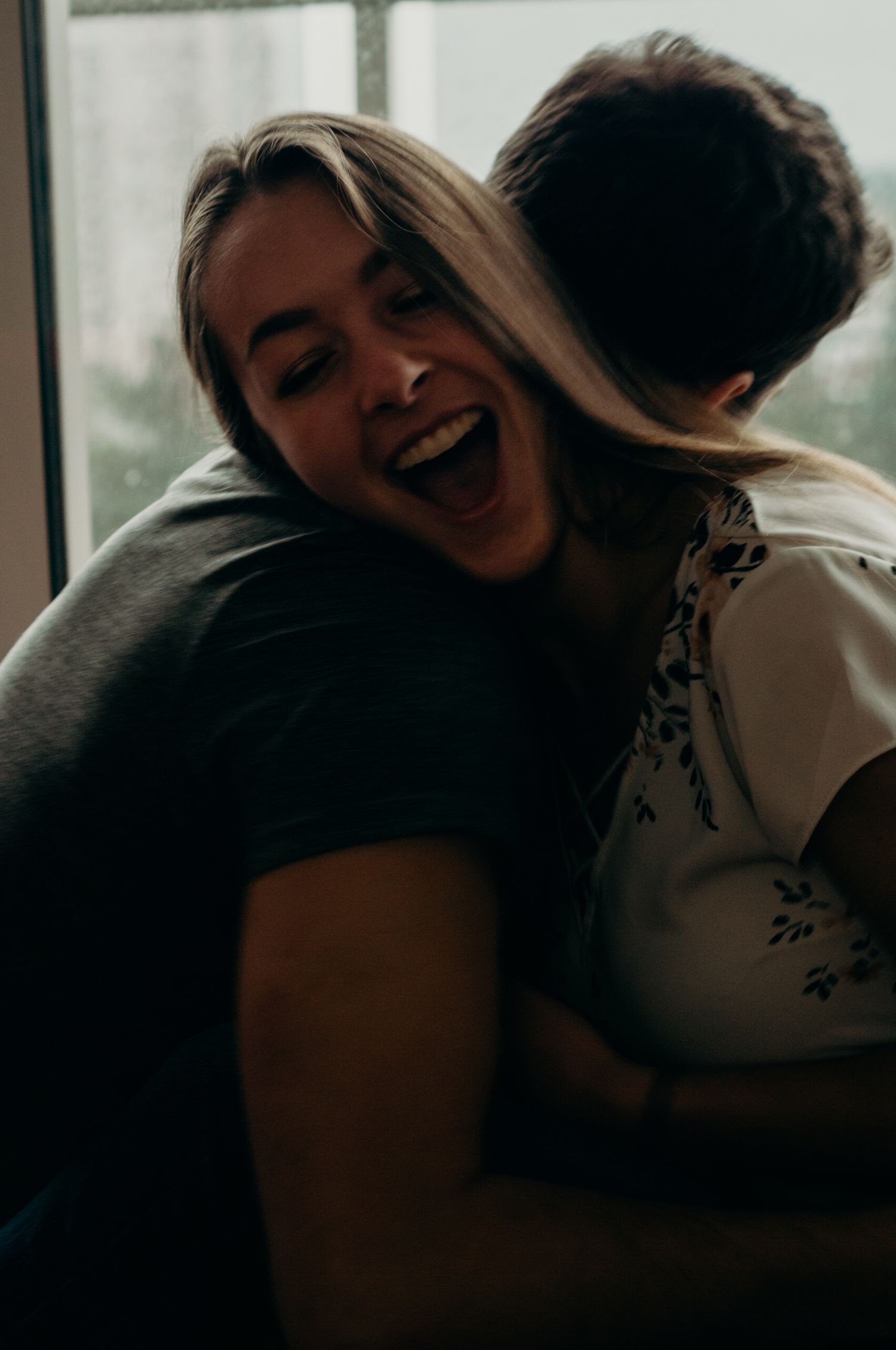Woman laughs as she's tickled lovingly by her boyfriend in their home.