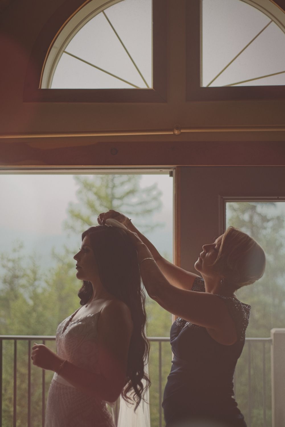 Bride's mother attaches her veil, helping her get ready before her wedding ceremony.