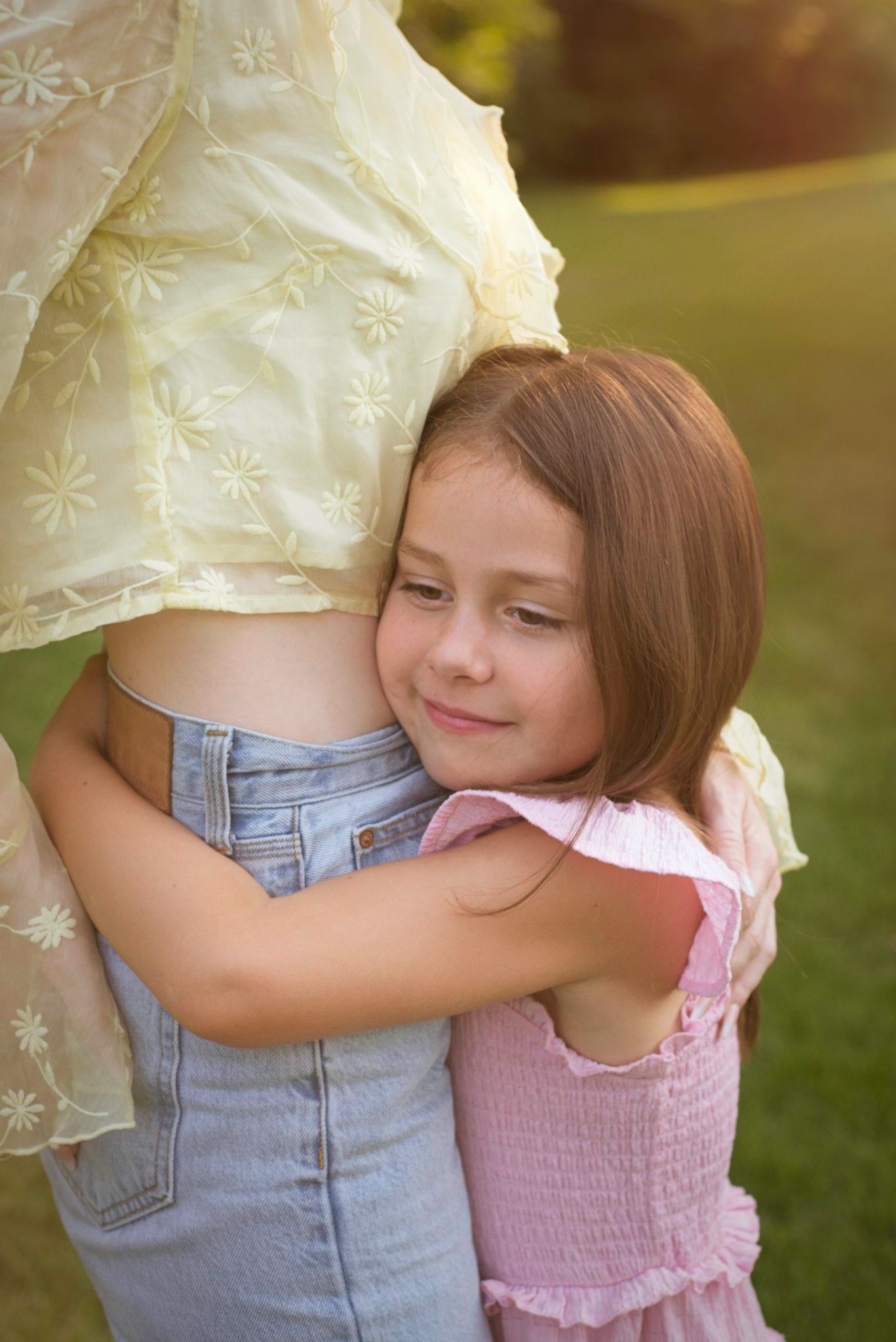 Child hugging her mom around her tummy looking content and safe.