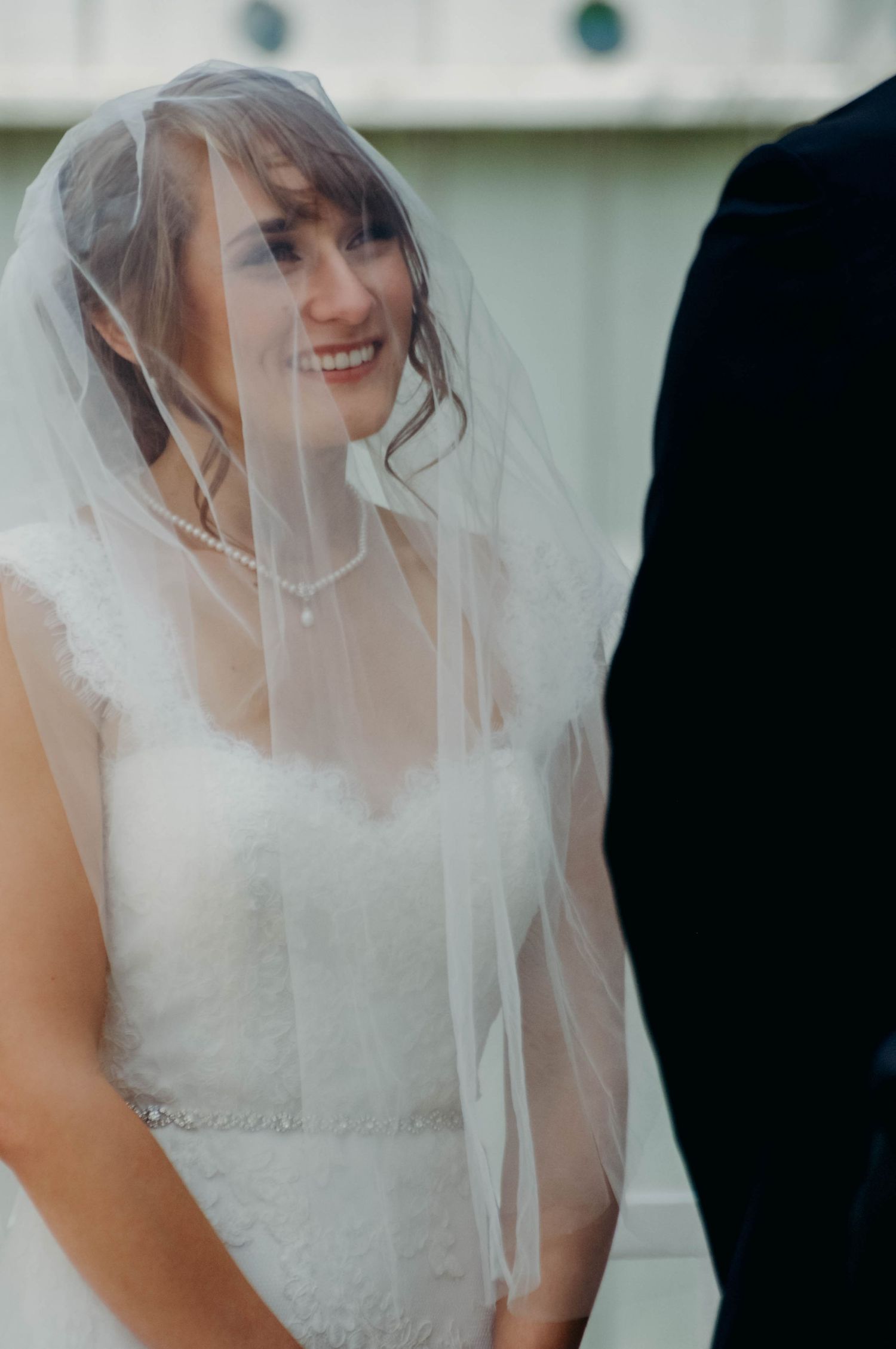 Bride looking up under her veil admiringly at her groom during the wedding ceremony.