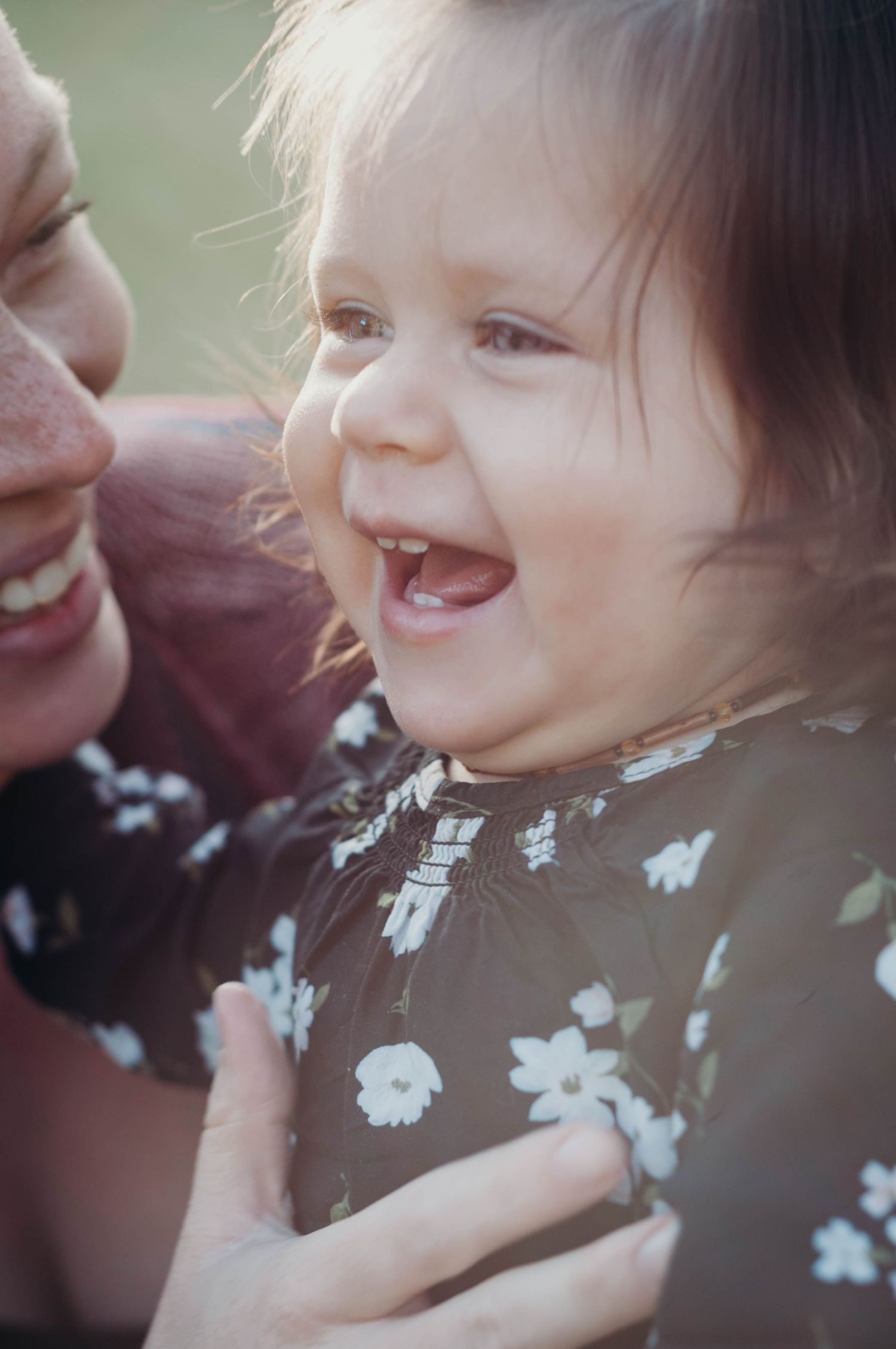 Baby laughs while being held by her mom.