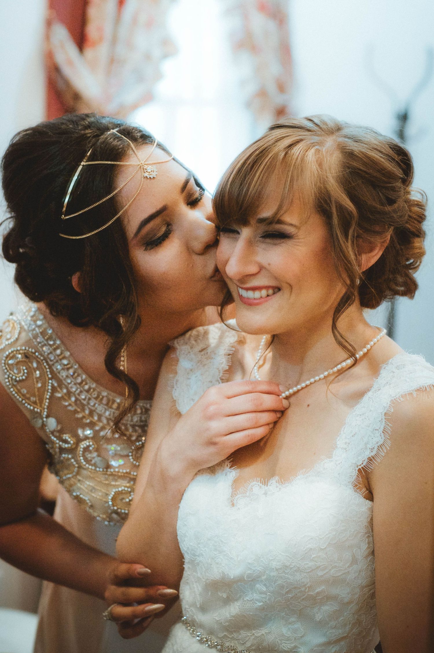 Bridesmaid kissing the cheek of the bride before the wedding.