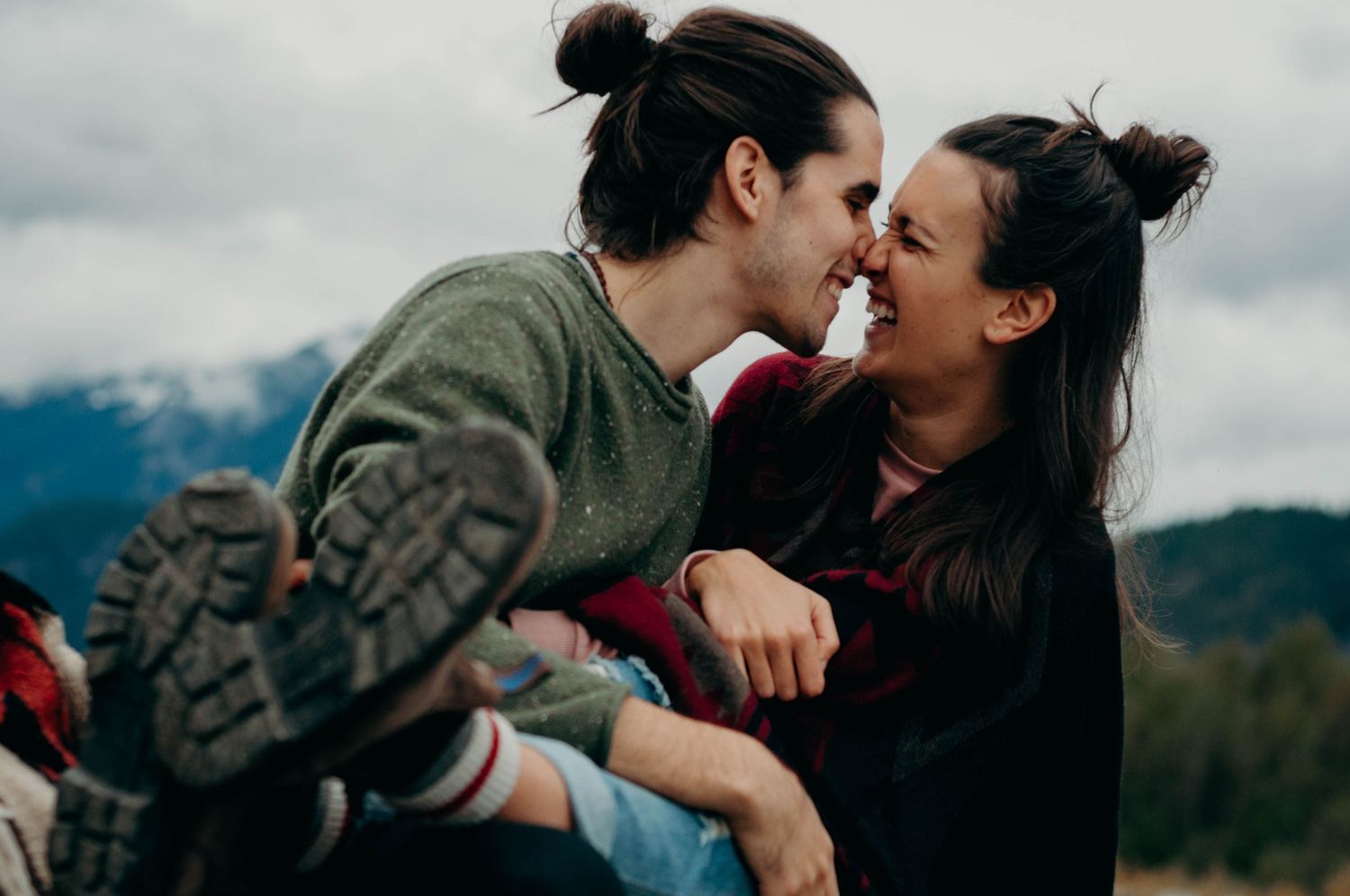 Engaged couple smush noses together and laugh.