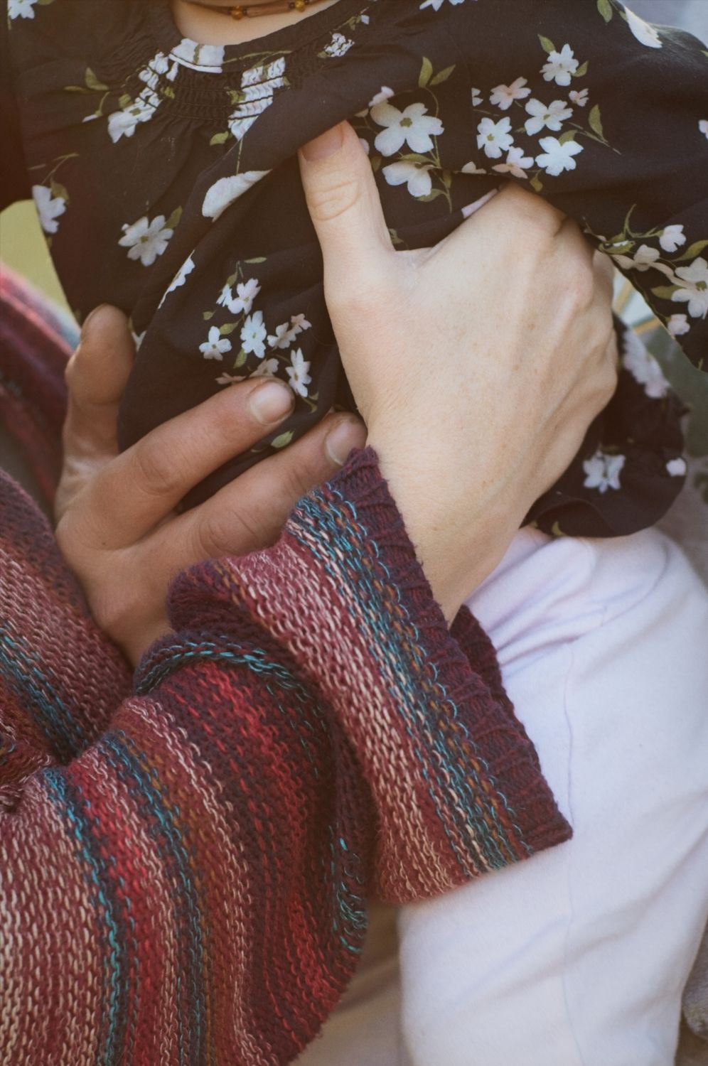 Mom and dad's hands wrapped around baby's tummy, holding her close.